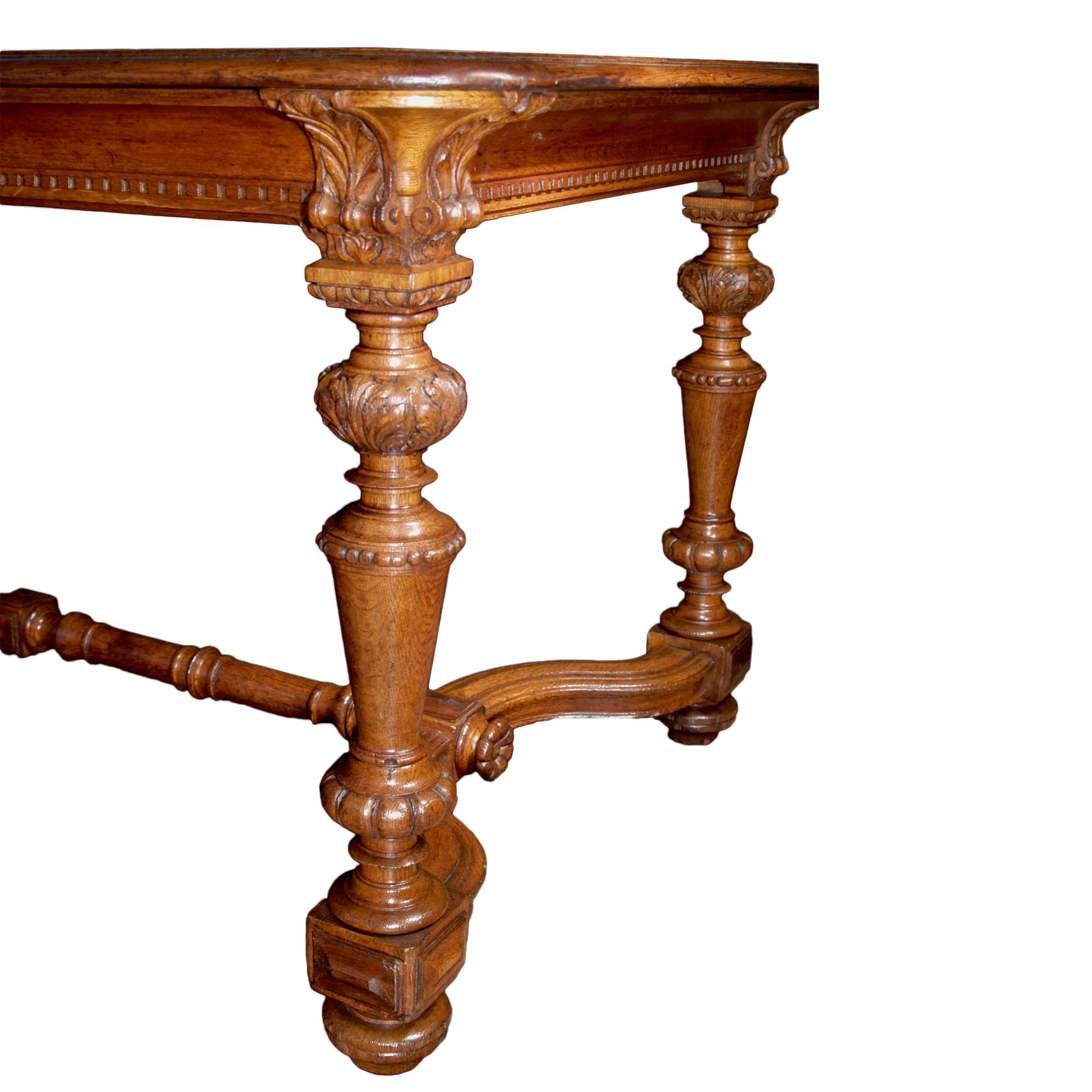 An attractive country French 19th century Louis XIV st. Honey-colored oak center/dining table. The legs with a Corinthian capitol-like carvings have baluster shapes decorated by acorn leaves ending by 'boule' shaped supports above the original brass