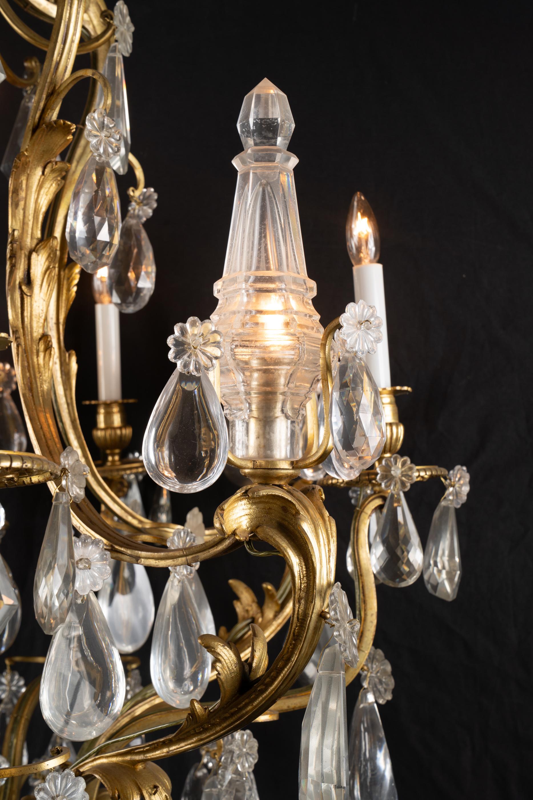 Splendido esempio di stile Luigi XV, questo lampadario in bronzo del XIX secolo presenta gocciolatori, coppe per candele e bobeches in bronzo ed è decorato con plaquette di cristallo tagliato di varie forme. I bracci di questo lampadario antico