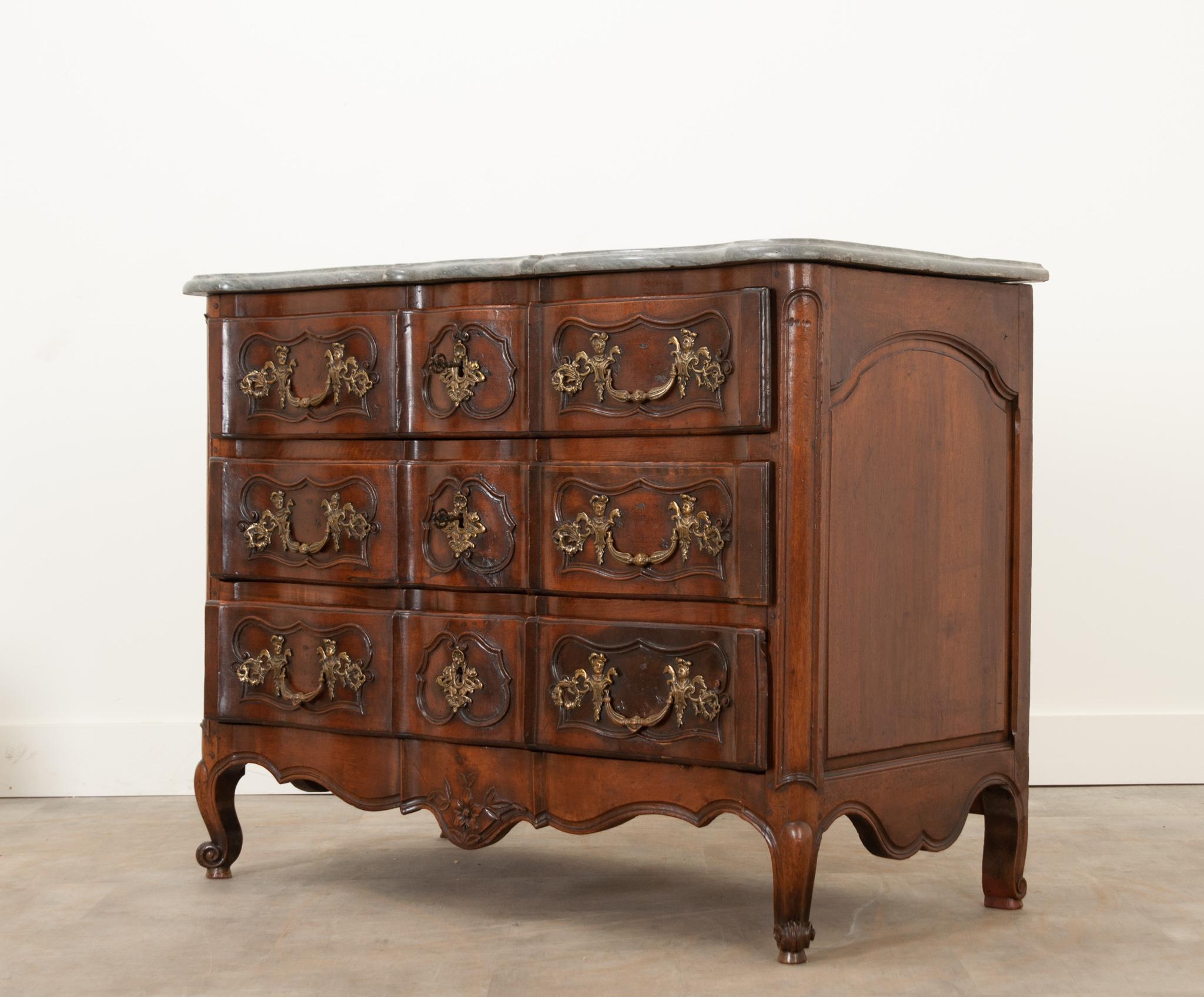 This handsome Louis XV style commode circa 1800 or earlier. A fantastic charcoal marble top with a molded edge, shaped in the same fashion as the body. A bank of three drawers features impressive cast brass ormolu pulls and escutcheons. Two keys are