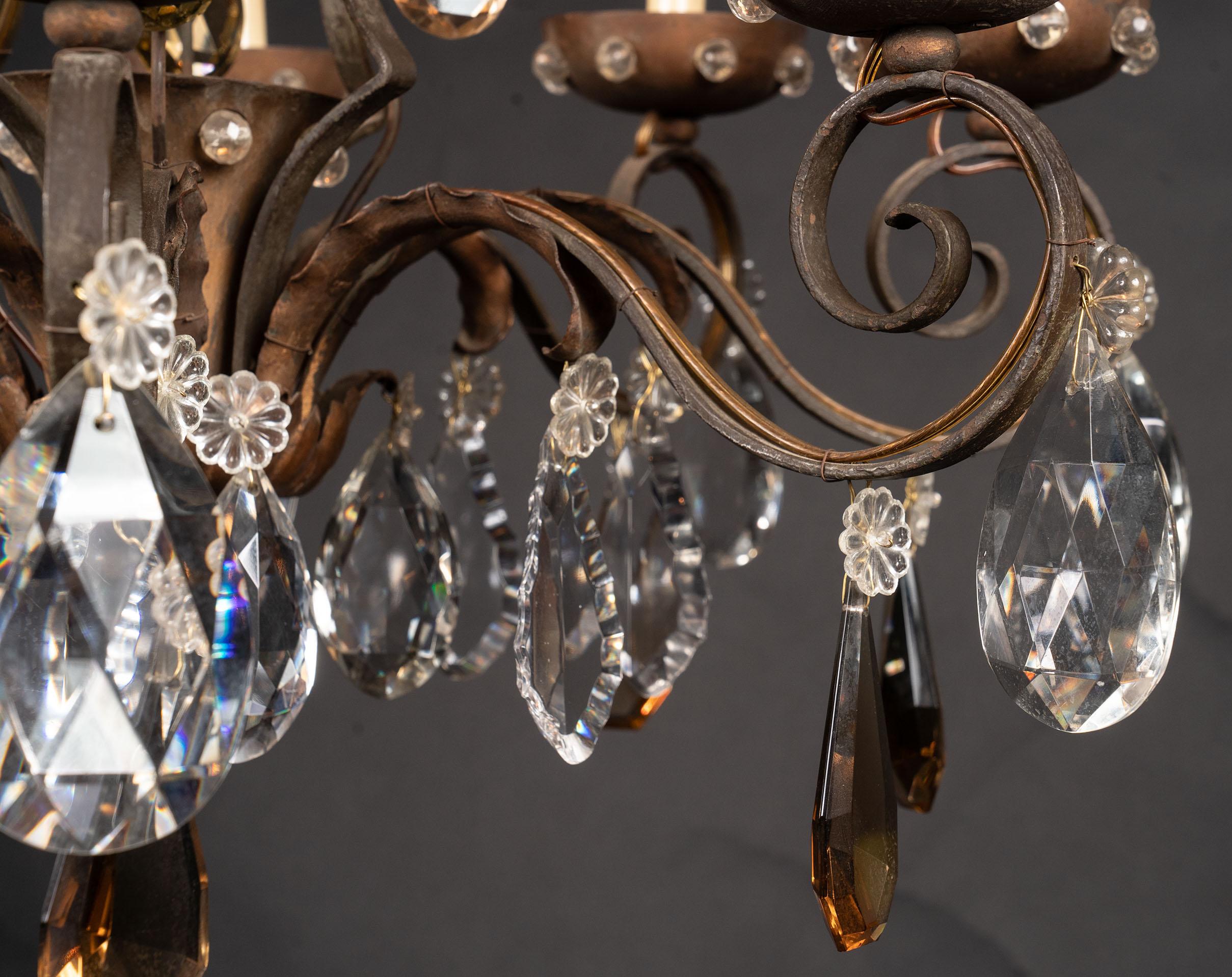 This beautiful Louis XV style chandelier features the bird cage like shape classic to the period, and is made of iron and draped in a variety of crystals. The French light fixture dates back to the 19th century and plays host to crystal plaquettes