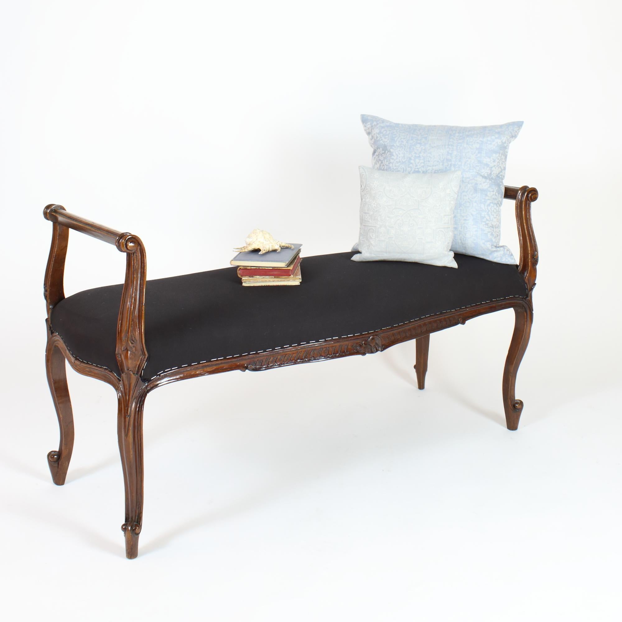 An elegant late 19th/early 20th century Louis XV banquette or window seat carved in solid walnut featuring scrolled arms and rails, the shaped padded seat above a serpentine frieze carved with rocaille and leaves, the whole supported on finely