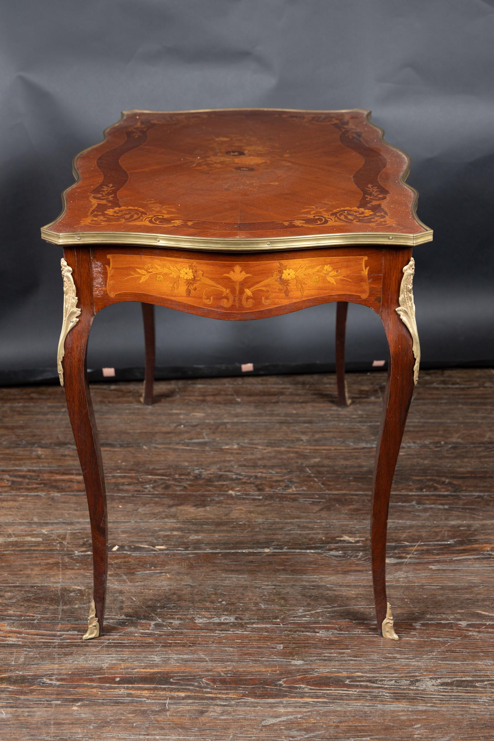 Cette magnifique table à écrire en marqueterie présente un beau plateau serpentin à bandes de laiton, des montures en bronze et un grand tiroir. La marqueterie florale est détaillée et équilibrée. Le bureau date du 19e siècle et représente avec