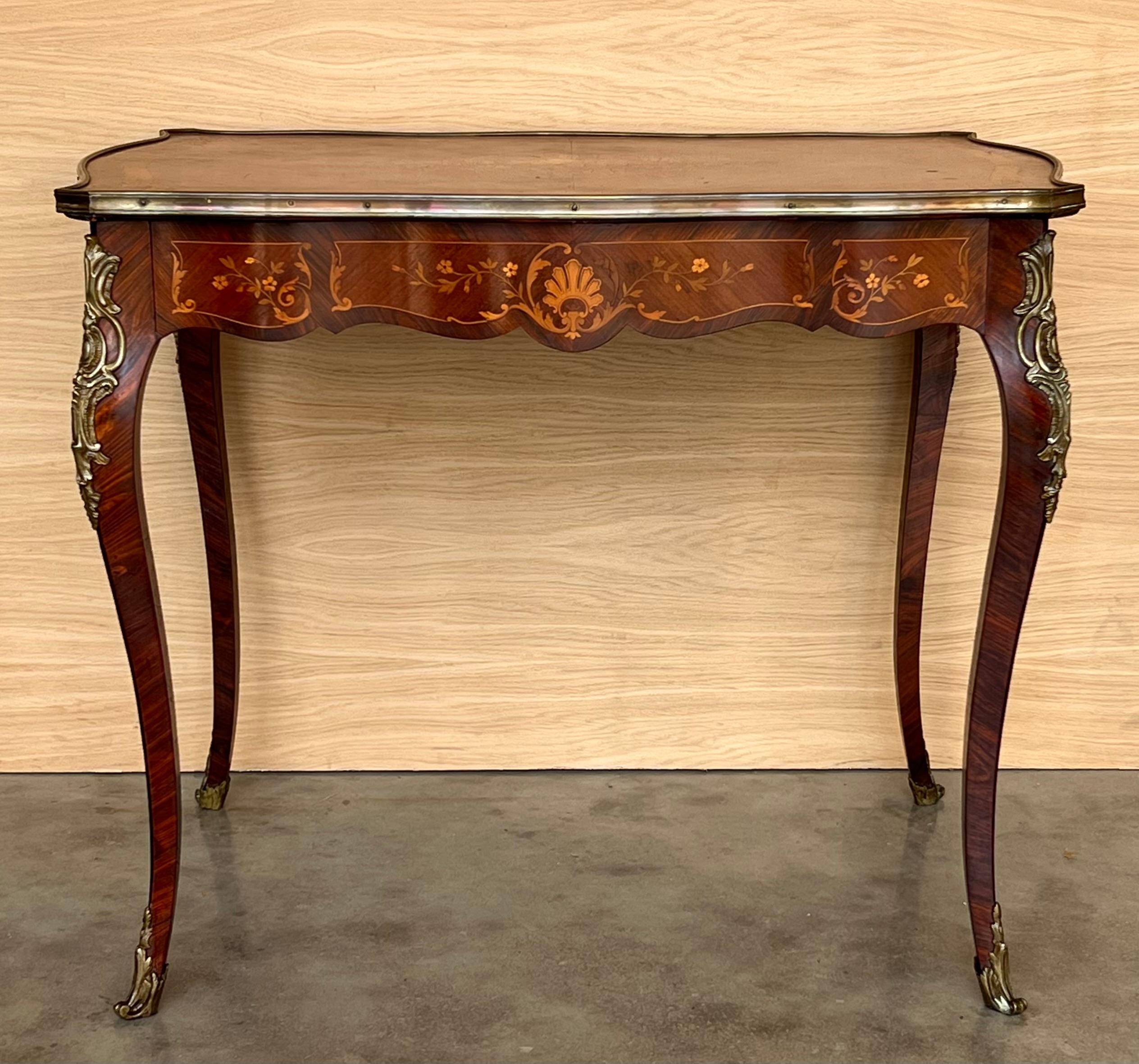 Cette magnifique table à écrire en marqueterie présente un beau plateau serpentin à bandes de laiton, des montures en bronze et un grand tiroir. La marqueterie florale est détaillée et équilibrée. Le bureau date du 19e siècle et représente avec