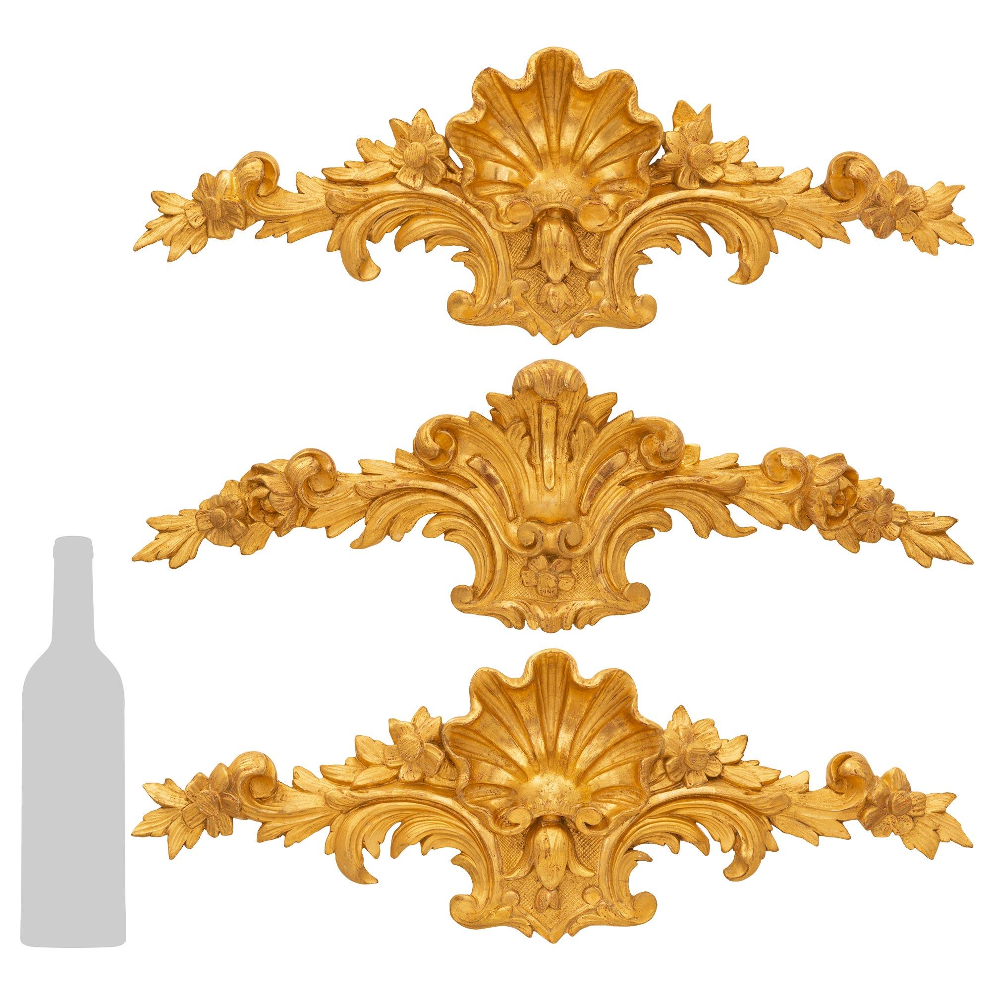 Ensemble de trois plaques murales en bois doré sculpté de style Louis XV du XIXe siècle. Chacune des plaques présente de charmantes fleurs épanouies richement sculptées au milieu de superbes motifs feuillagés et de merveilleux mouvements. Au centre