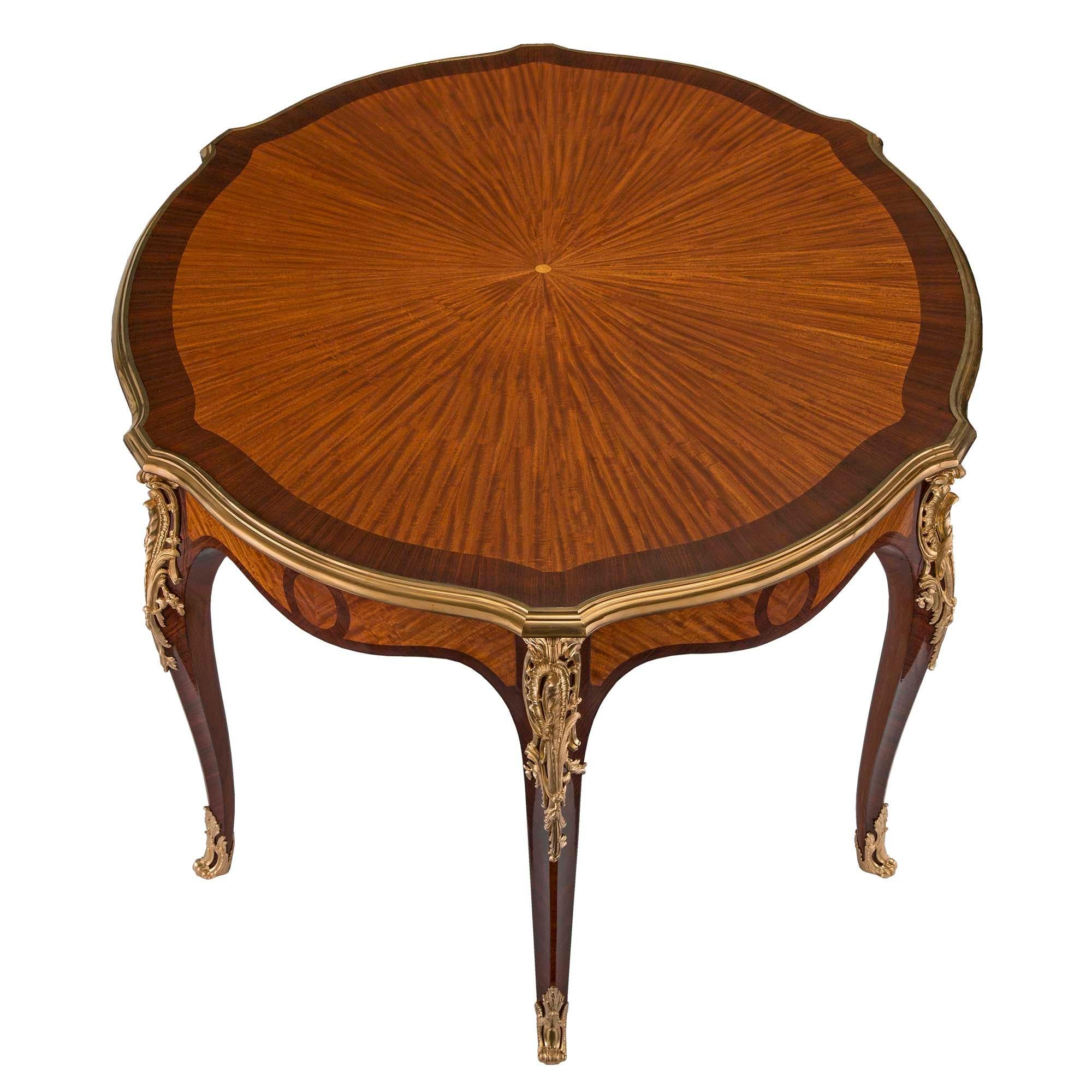 A stunning and rare French 19th century Louis XV st. kingwood, tulipwood and ormolu dining or center table. The table is raised by six elegant cabriole legs with richly chased pierced wrap around sabots and fine pierced ormolu foliate mounts. The