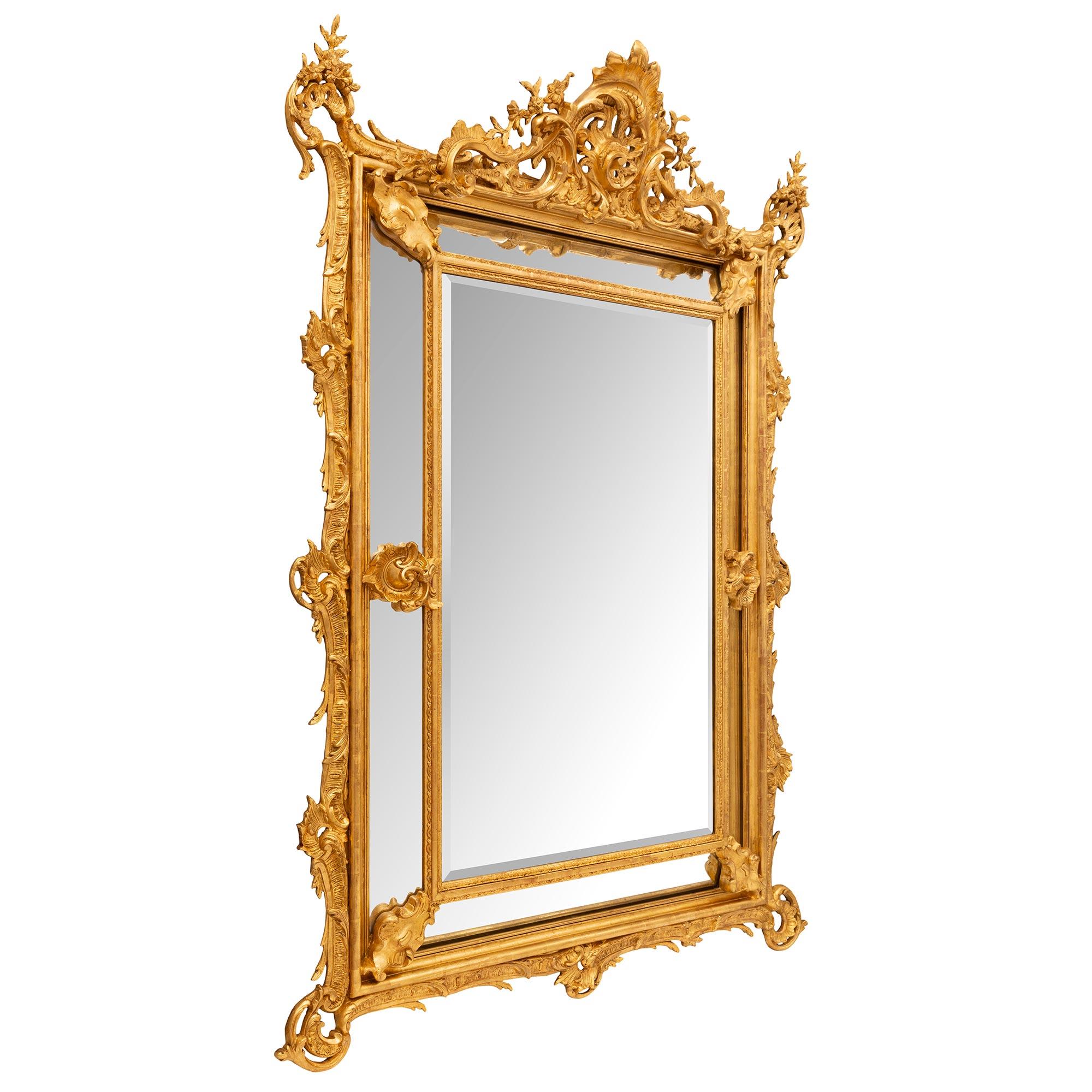 A stunning and extremely unique French 19th century Louis XV st. double framed giltwood mirror. The original central beveled mirror plate is framed within a mottled band with delicate foliate designs. The original outer mirror plates are centered by