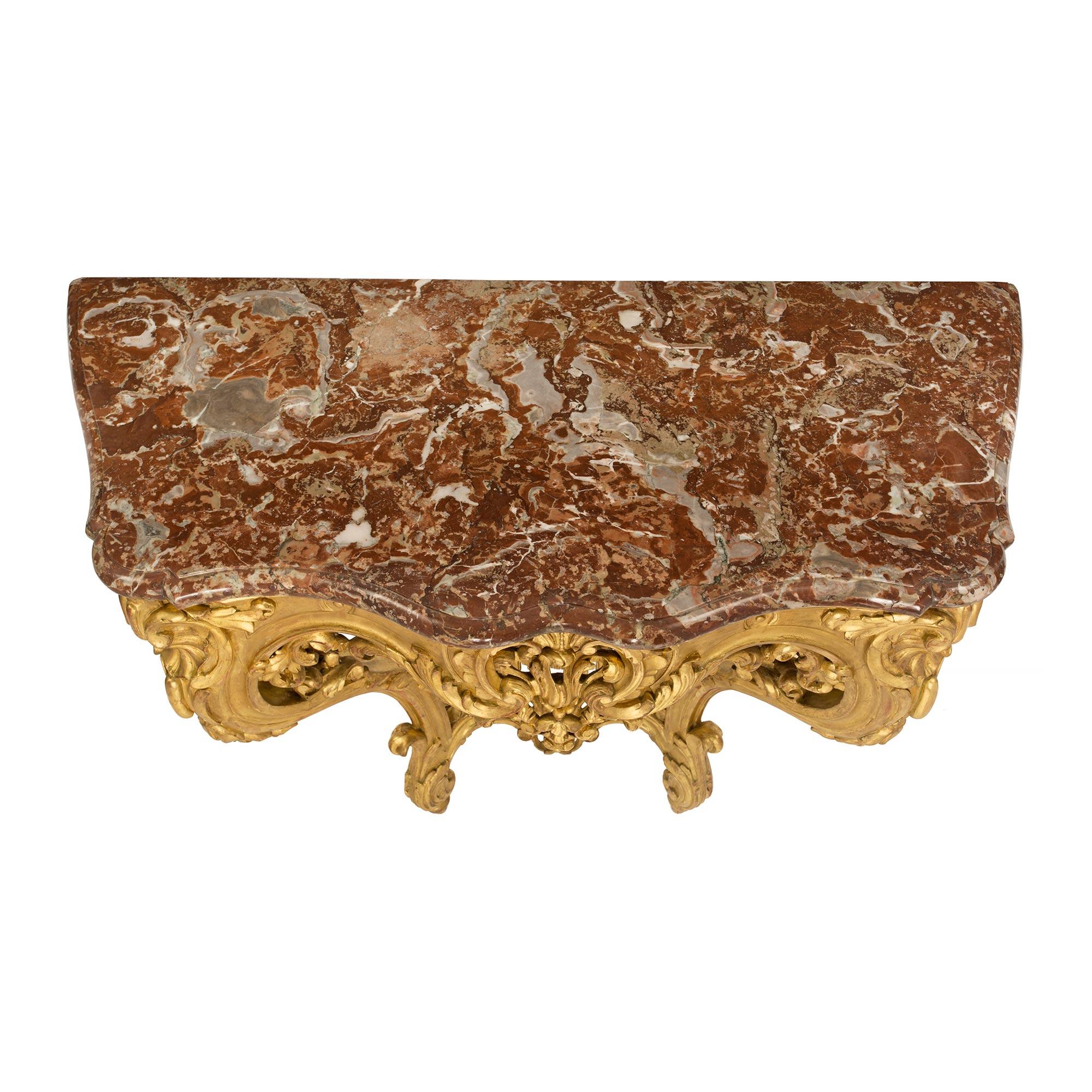 An elegant French 19th Century Louis XV st. giltwood and marble wall mounted console. The console is raised by fine topie shaped feet below elegant cabriole legs adorned with richly carved acanthus leaves and floral movements. The legs are connected