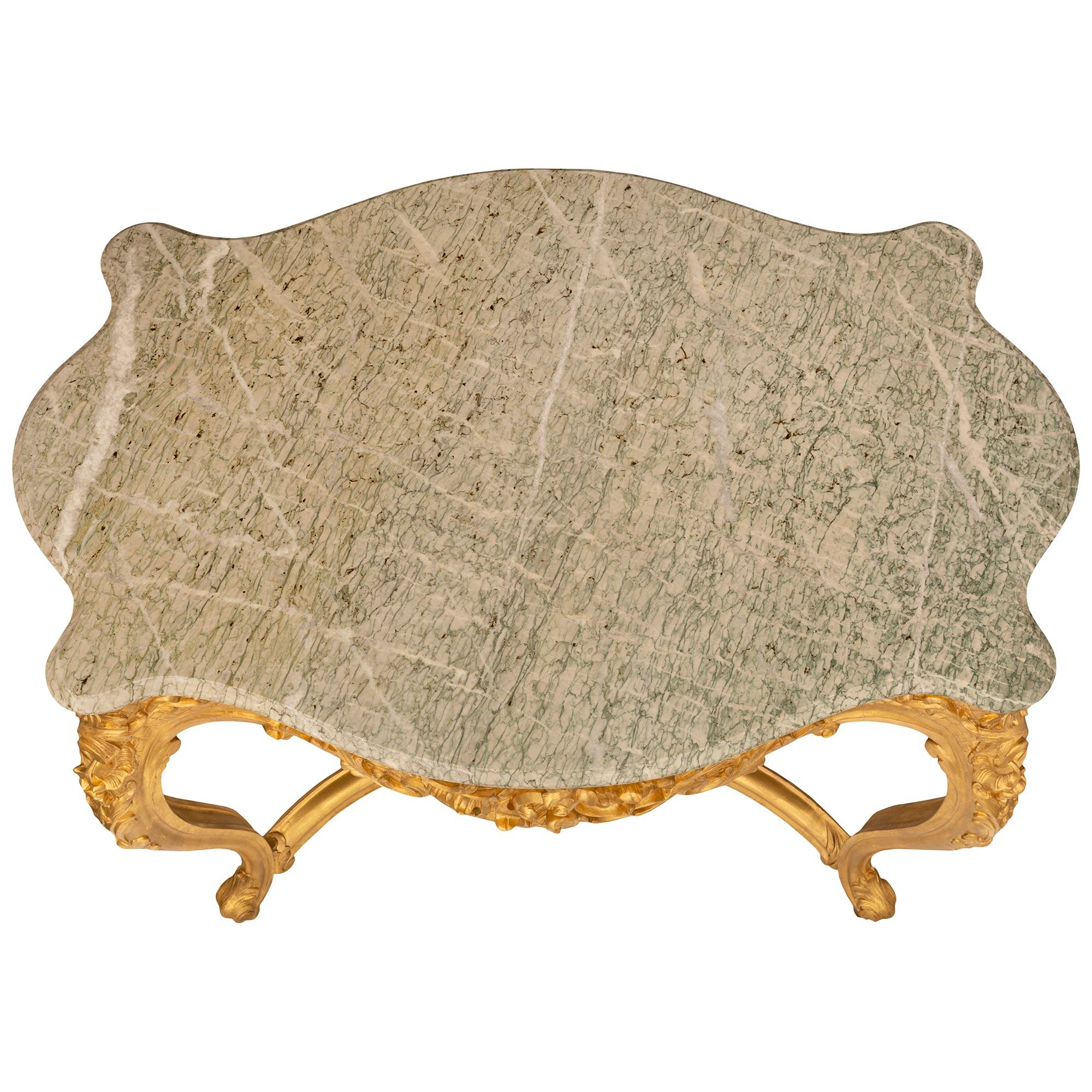 A beautiful and most elegant French 19th century Louis XV st. giltwood and Vert Campan marble center table. The scalloped table is raised by lovely cabriole legs with scrolled acanthus leaf feet connected by an elegantly curved X shaped stretcher