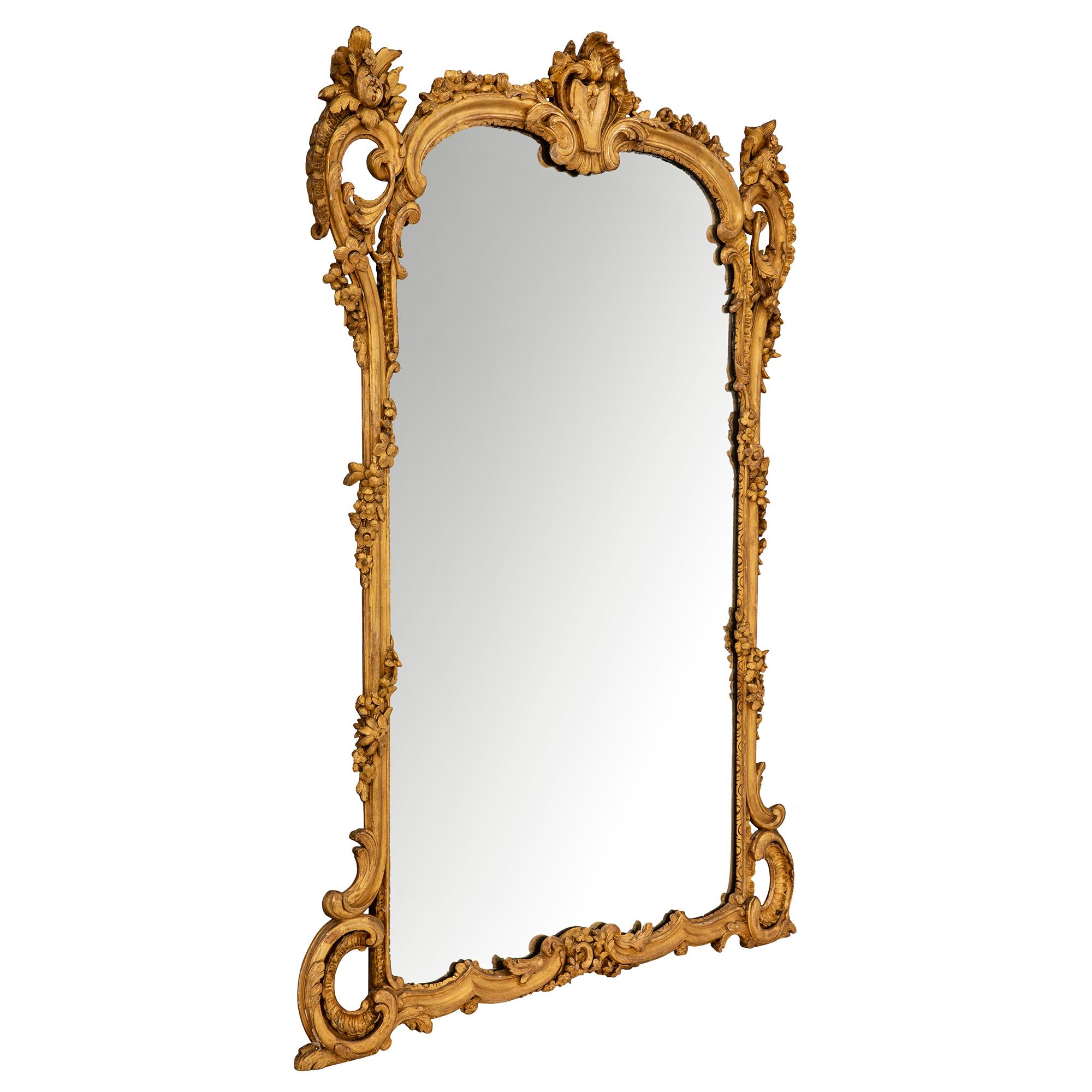 Un très élégant miroir français du 19ème siècle en bois doré de style Louis XV. La plaque de miroir originale est encadrée dans un beau cadre chiné. À la base, on trouve de jolis motifs à volutes avec de saisissantes volutes sculptées en roseau de