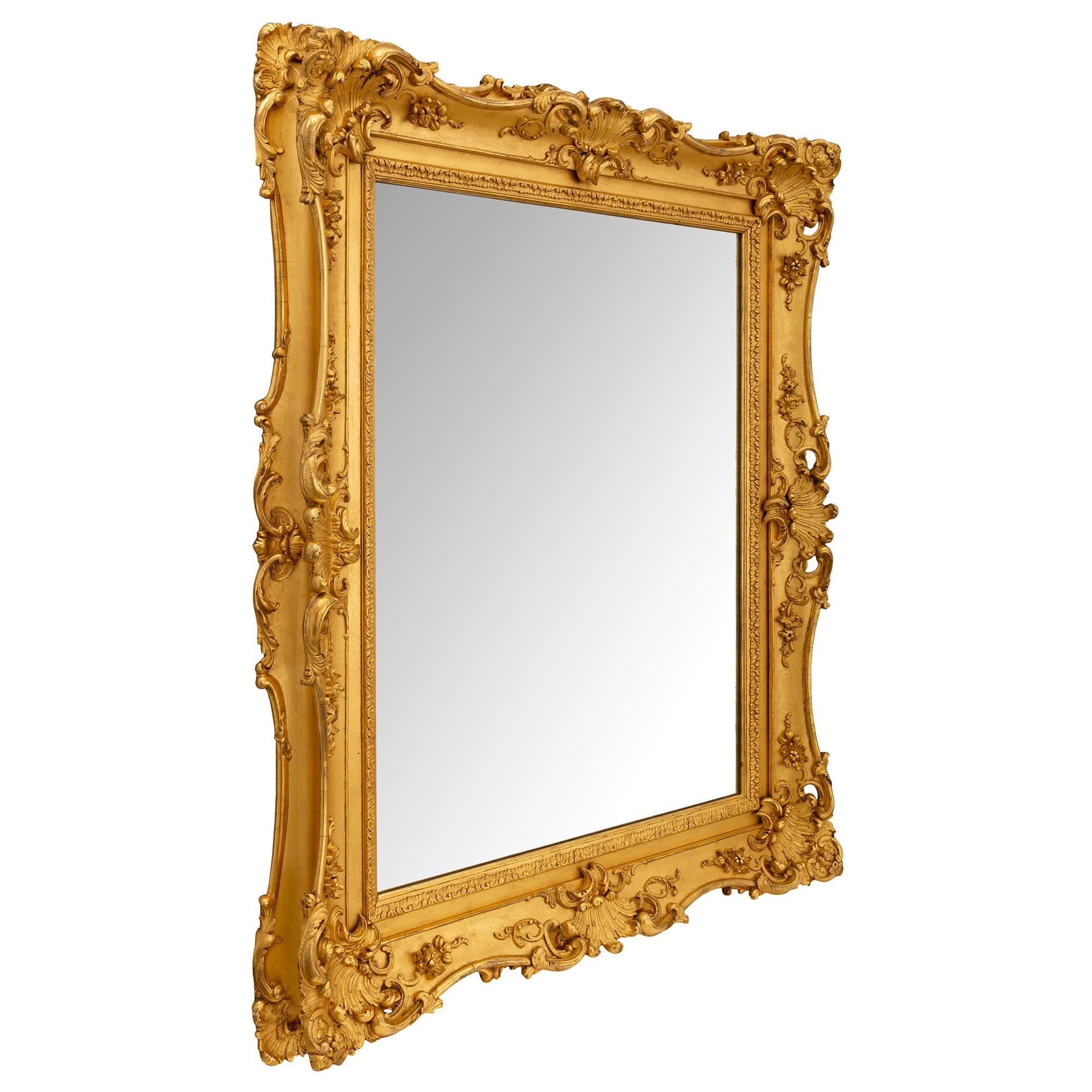 A striking French 19th century Louis XV st. giltwood mirror. The mirror retains its original mirror plate framed within a fine straight mottled border with a fine wrap around foliate band. The frame displays an elegant and most decorative scalloped