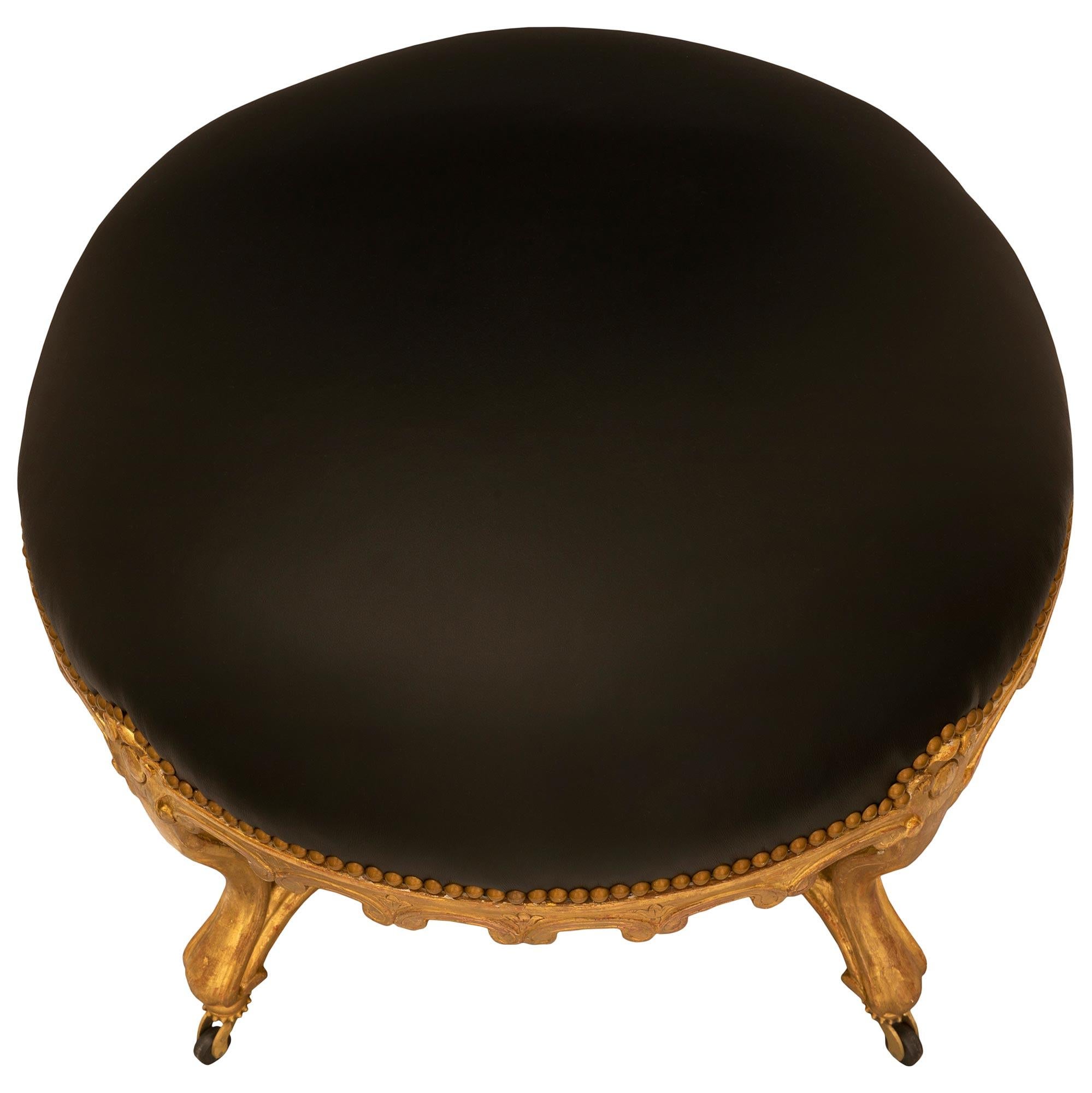 An elegant French 19th century Louis XV st. giltwood stool. The circular stool is raised by elegant casters with a fine wrap around beaded band below most decorative cabriole legs with carved mottled borders and each connected by a beautiful