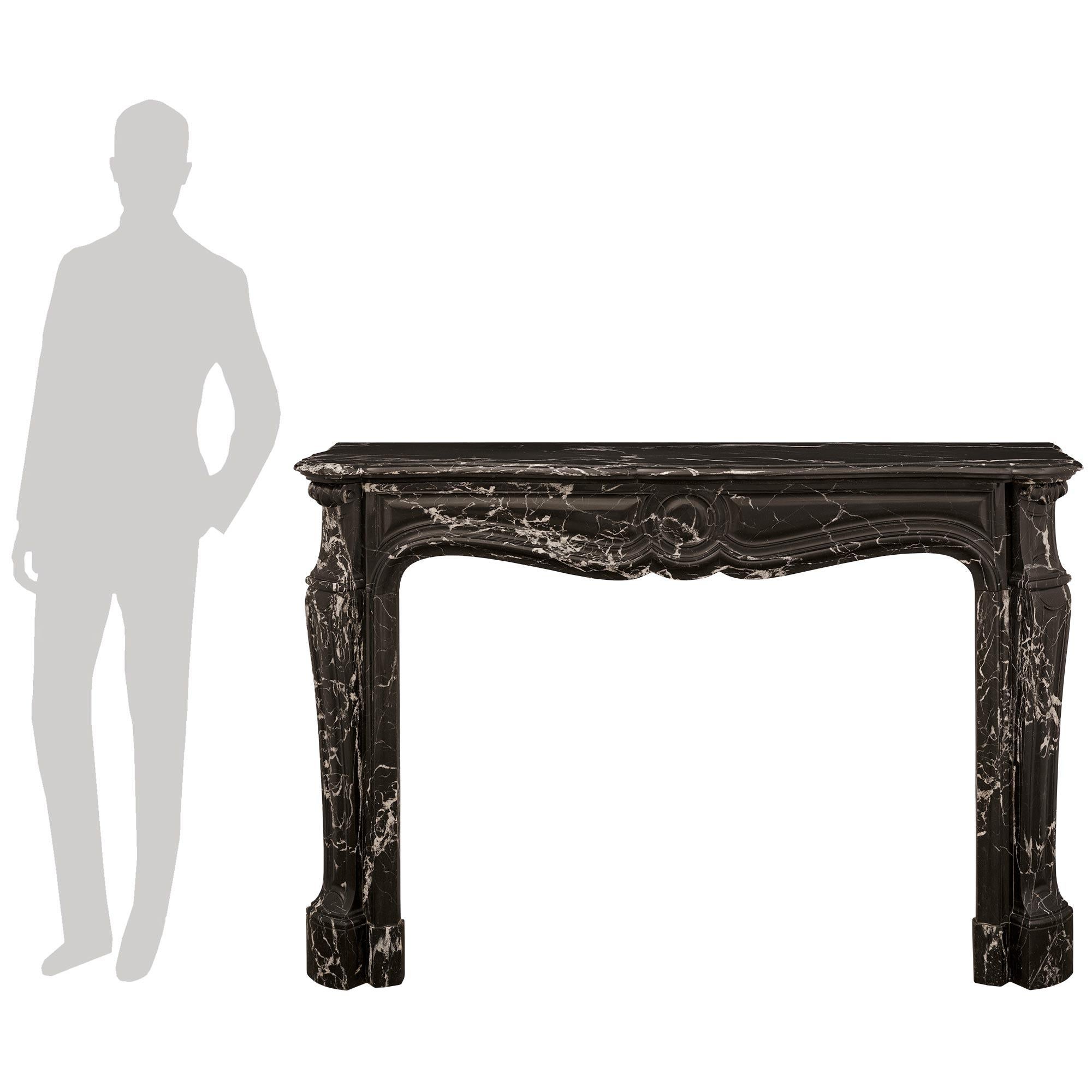 Un bellissimo caminetto francese del XIX secolo in stile Luigi XV. Questo meraviglioso caminetto si erge su stipiti a voluta intagliati con capitelli superiori a voluta e prese d'aria laterali in ottone. La fascia con bordi screziati ha un grande