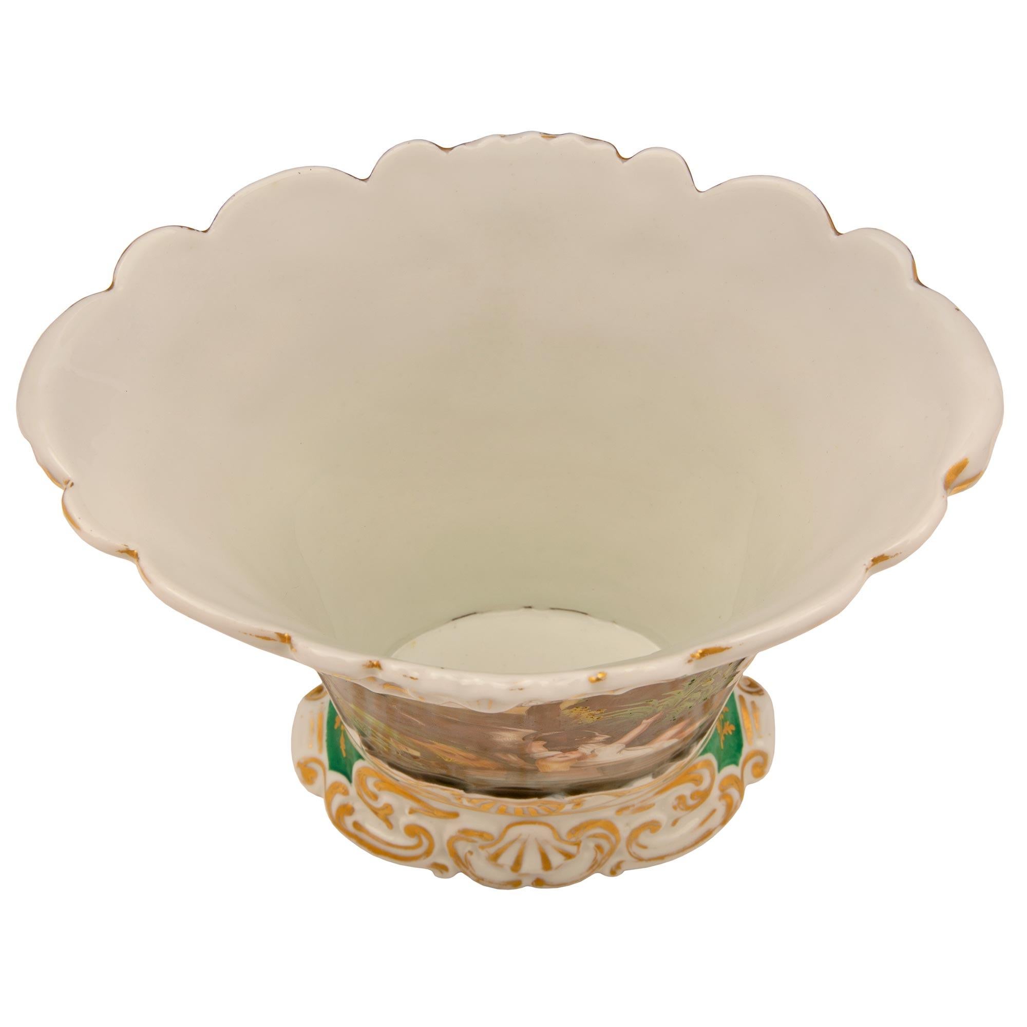 Eine äußerst charmante und sehr dekorative französische Porzellanvase aus dem 19. Jahrhundert im Stil Louis XV, handbemalt. Die Vase wird von einem schönen, verschnörkelten Blattsockel mit goldenen Akzenten getragen. Der leicht gewölbte Korpus zeigt