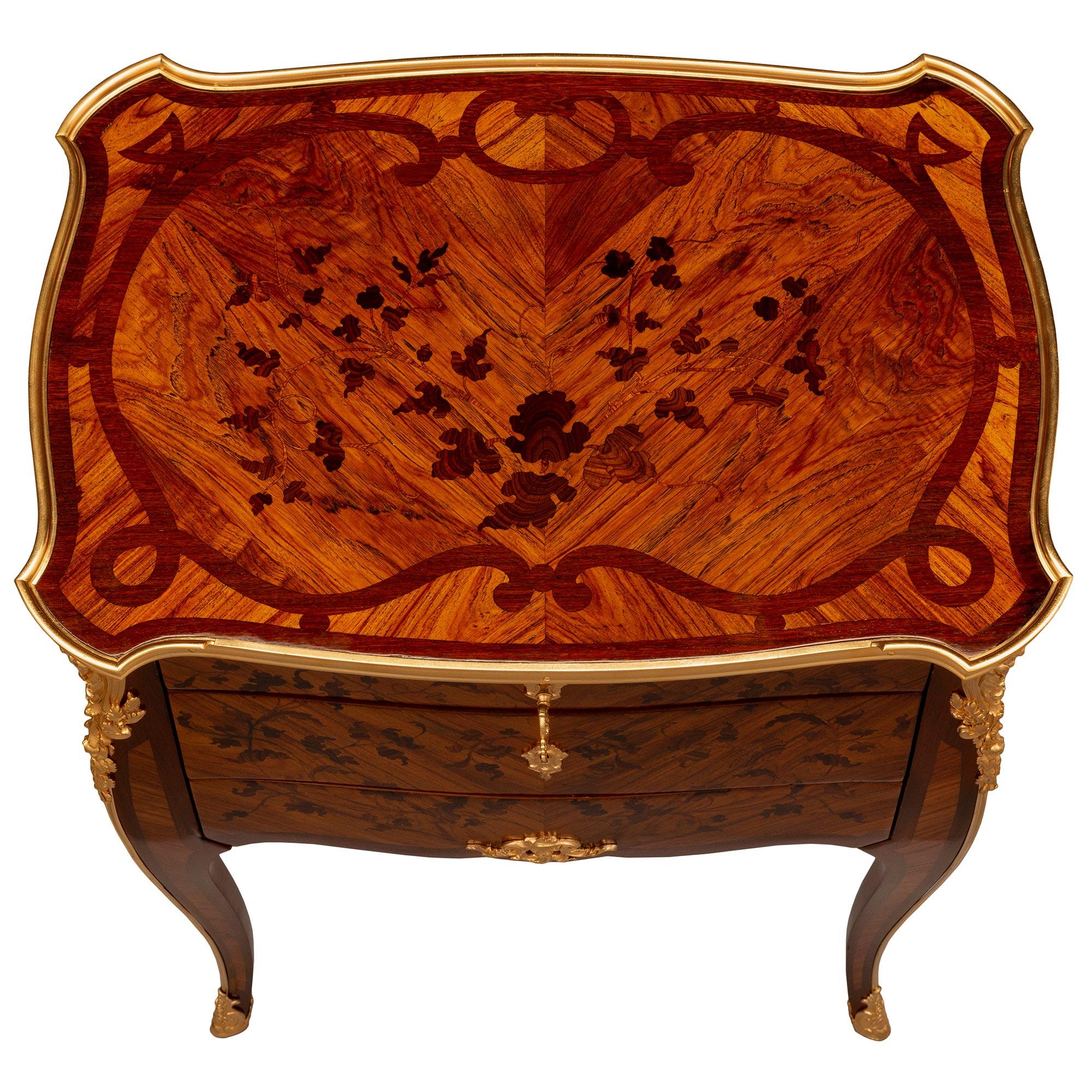 A stunning French 19th century Louis XV st. Kingwood, exotic wood, and ormolu side table signed by Durand. The three-drawer table is raised by elegant cabriole legs with exceptional fitted foliate ormolu sabots and chutes leading up each leg to