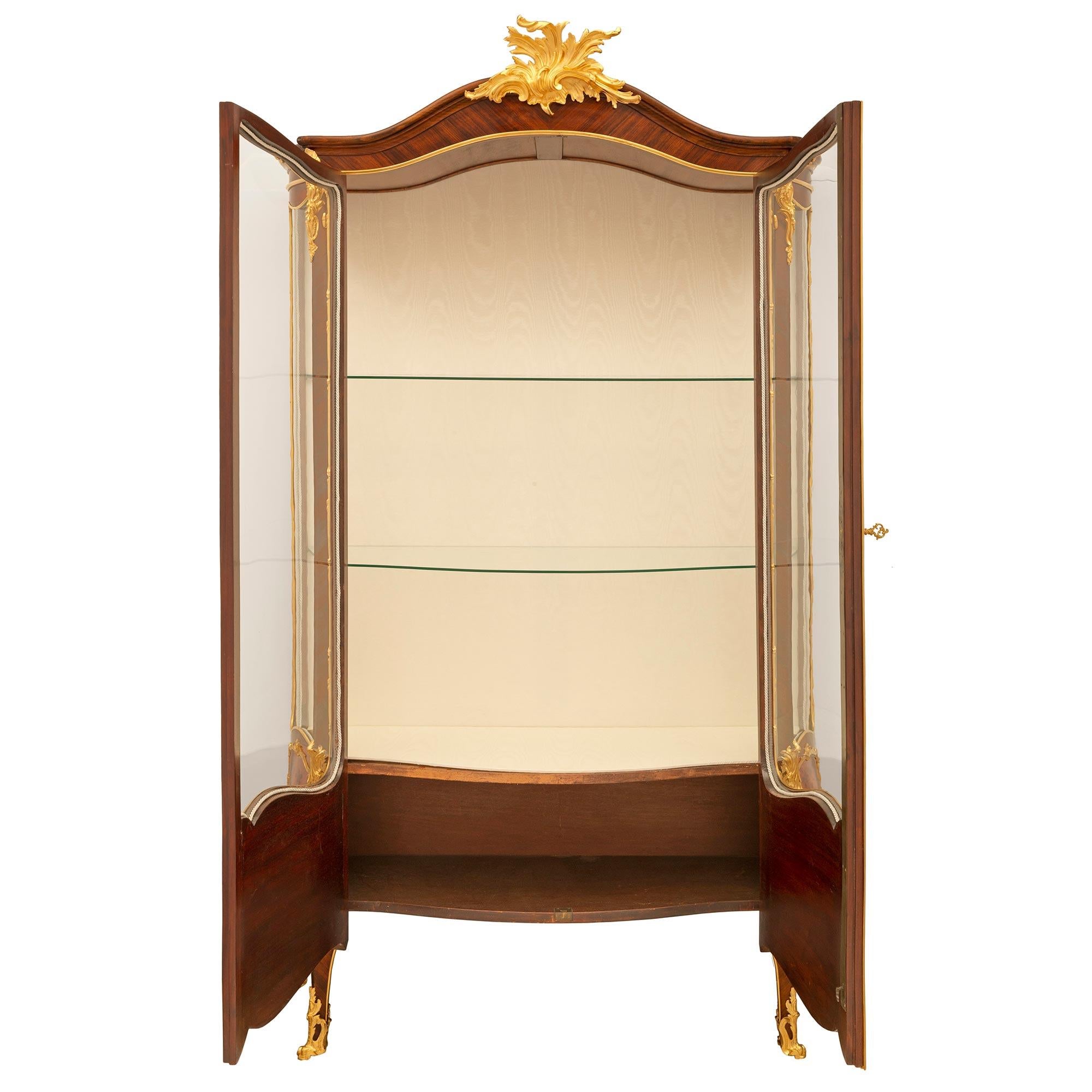 A stunning and extremely high quality French 19th century Louis XV st. Kingwood, Tulipwood, and ormolu cabinet vitrine attributed to François Linke. The two door cabinet is raised by elegant cabriole legs with superb pierced fitted foliate ormolu