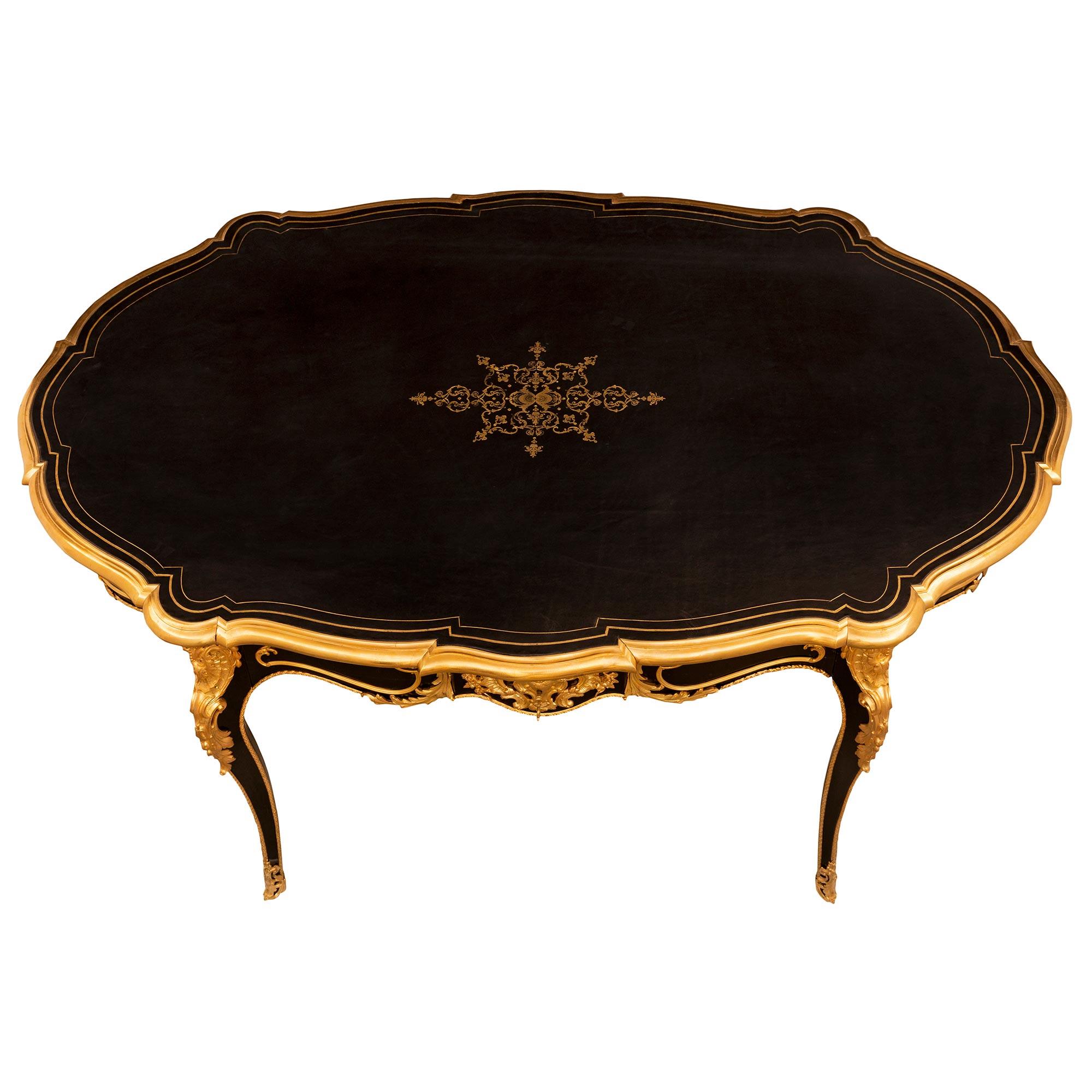 A most elegant and very high quality French 19th century Louis XV st. Napoleon III period ebony and ormolu center table/desk. The table is raised by very slender cabriole legs with exquisite pierced fitted foliate ormolu sabots with exceptional