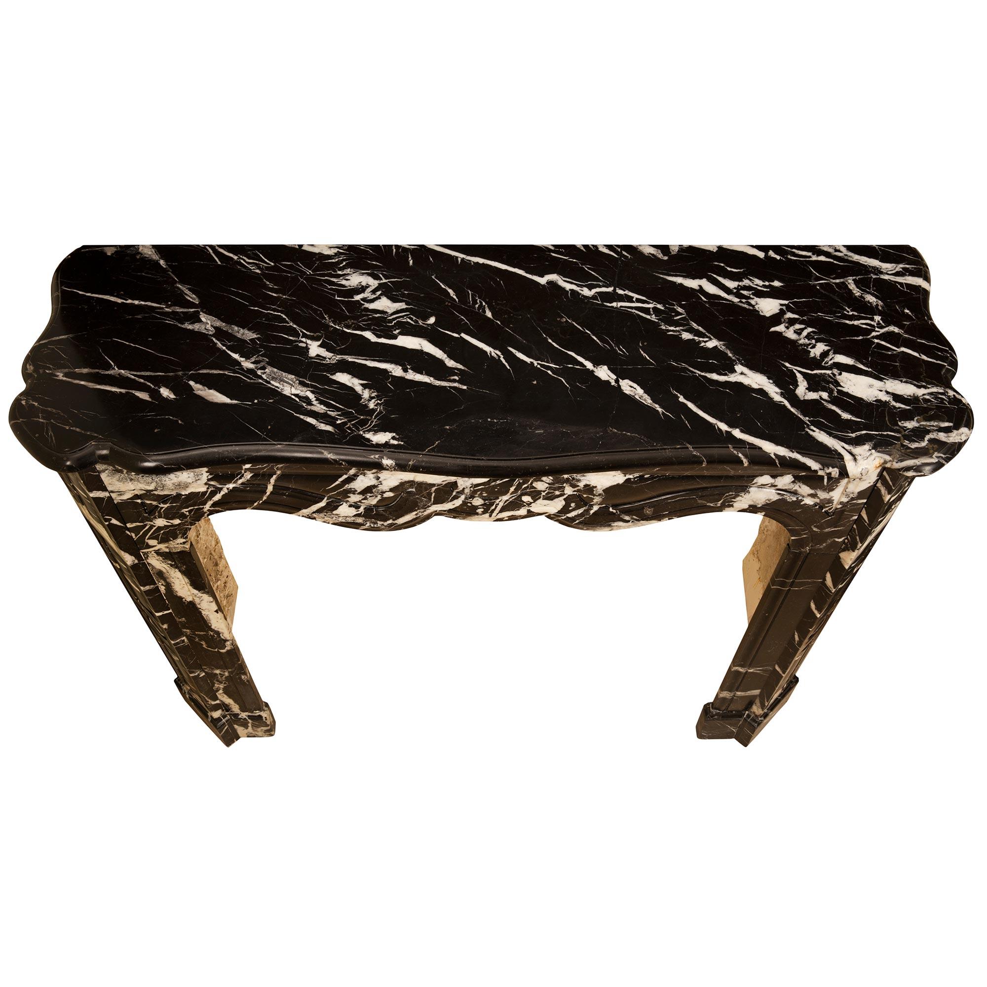 Une impressionnante cheminée en marbre ancien Louis XV st. Noir du XIXe siècle. Le manteau est surélevé par d'élégants jambages aux bases finement marbrées sous d'élégants motifs en creux, des cabochons, et des bouches d'aération circulaires en