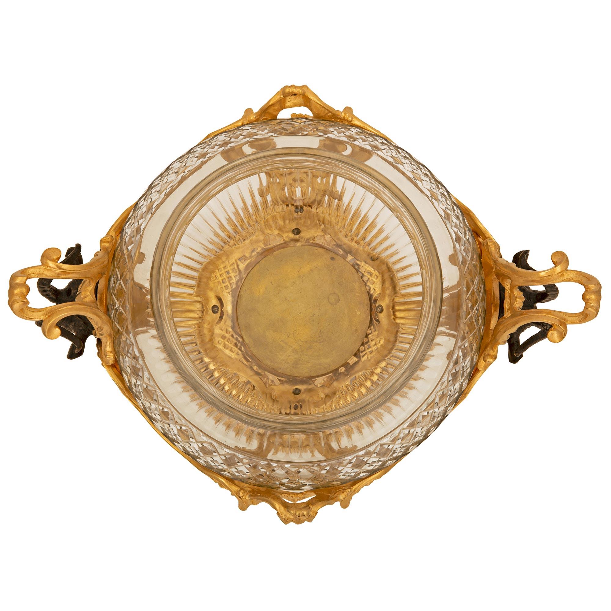 Remarquable et très unique centre de table Louis XV du 19ème siècle en bronze doré, bronze patiné et cristal de Baccarat. La pièce centrale est surélevée par une étonnante base percée avec de superbes motifs feuillus en volutes et un beau masque