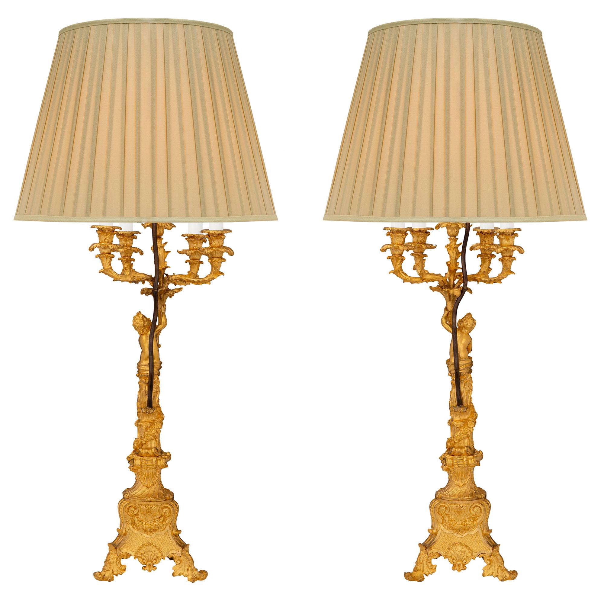 Soberbio par de candelabros franceses de ormolina del siglo XIX, estilo Luis XV, de muy alta calidad, montados en lámparas. Cada lámpara se eleva sobre una impresionante base trípode de lo más decorativa, con bellos pies con volutas y asombrosos