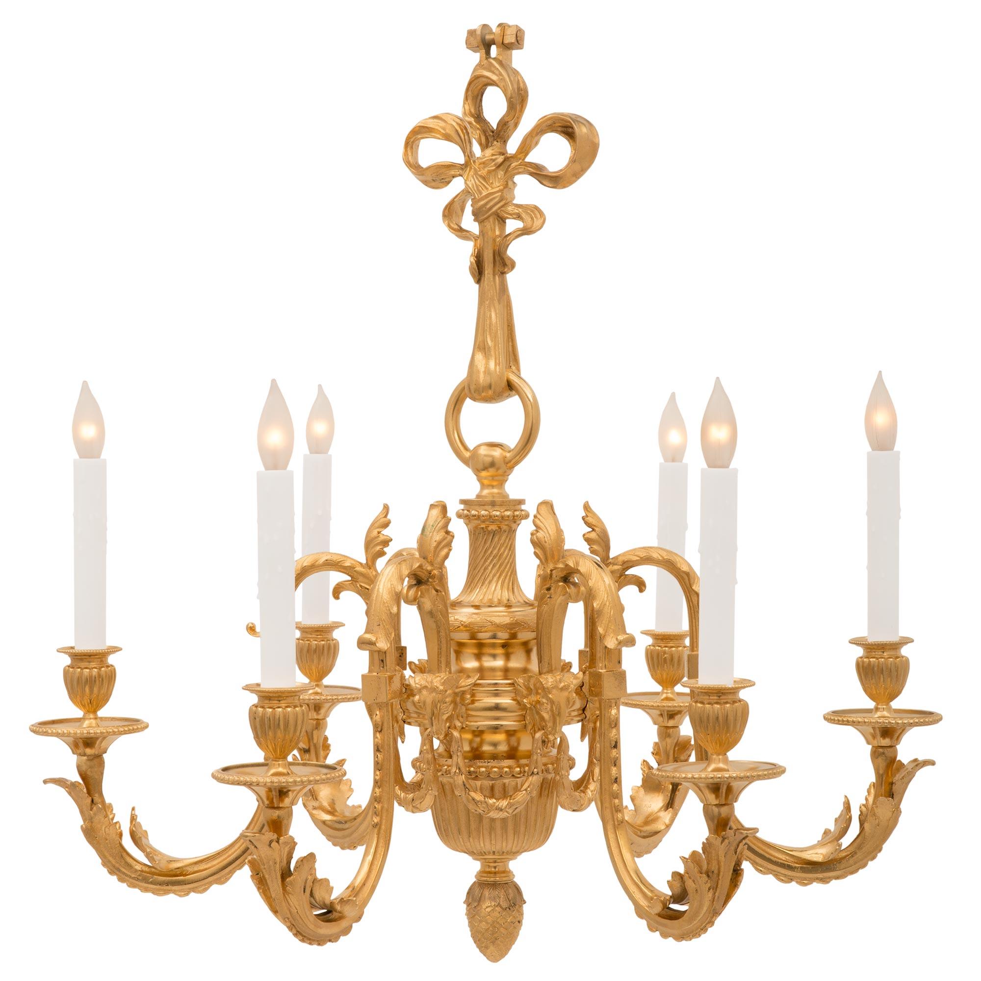 A charming French 19th century Louis XV st. ormolu chandelier. The six arm chandelier is centered by a beautiful finely detailed acorn finial below the reeded body. Each of the elegantly scrolled arms branches out from impressive rams heads