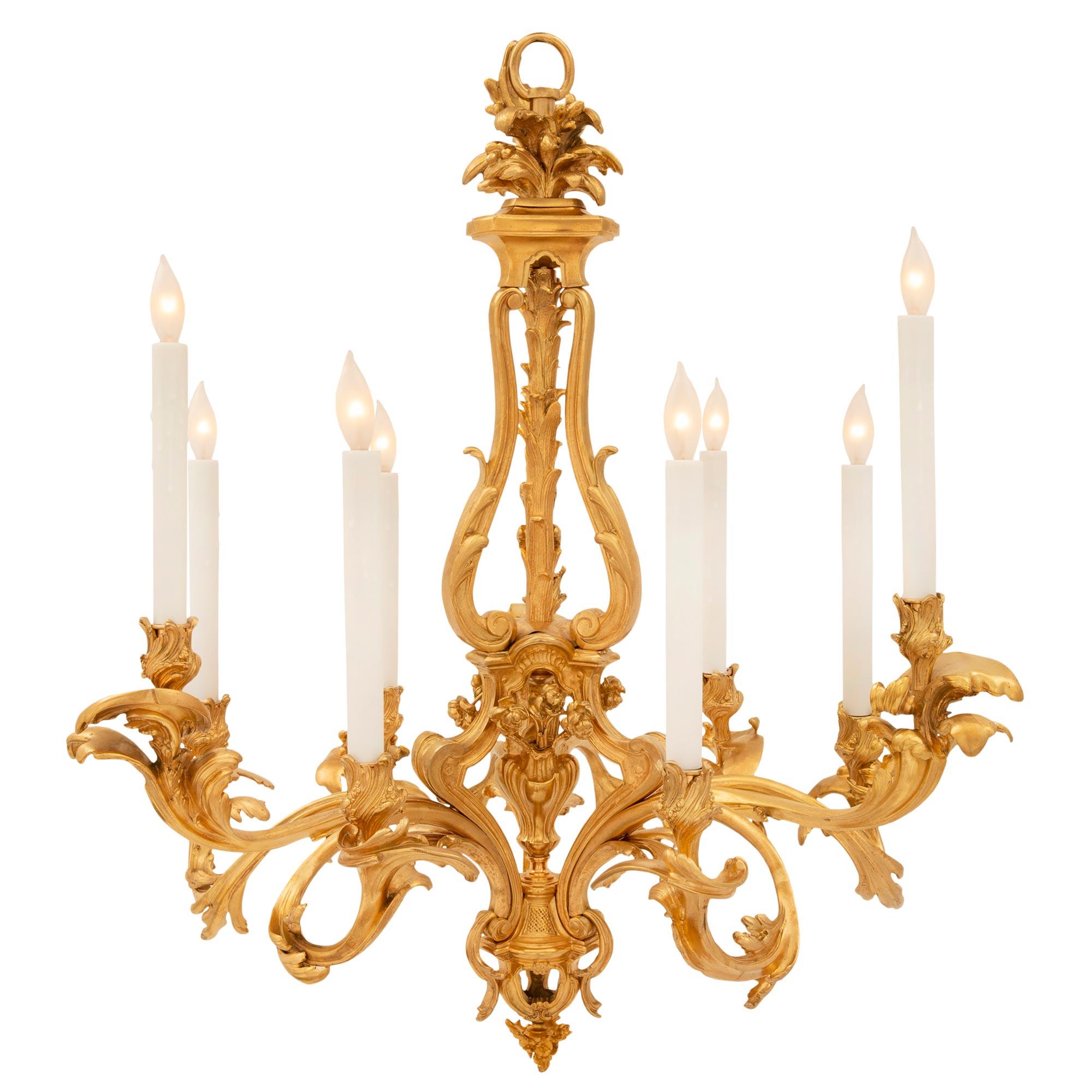 A stunning and extremely unique French 19th century Louis XV st. ormolu chandelier, signed by Vian and after a model by Jean-Jacques Caffieri. The nine arm chandelier is centered by a striking bottom floral finial below beautiful scrolled foliate