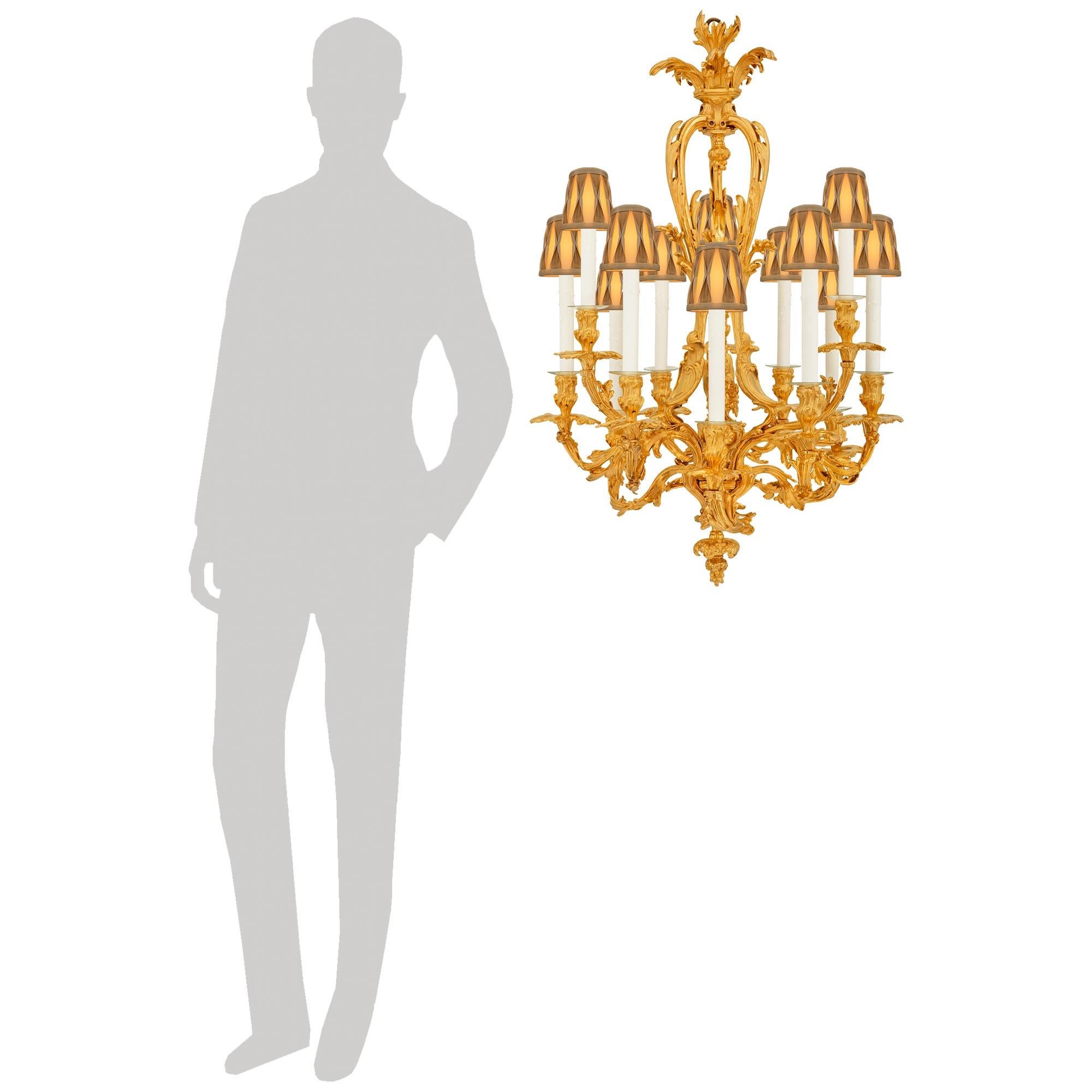 Un elegante e pregiato lampadario francese del XIX secolo in stile Luigi XV in Ormolu. Questo splendido lampadario a dodici luci è centrato da un terminale inferiore con bacche e disegni di foglie d'acanto che scorrono. Ognuno dei bracci a volute è