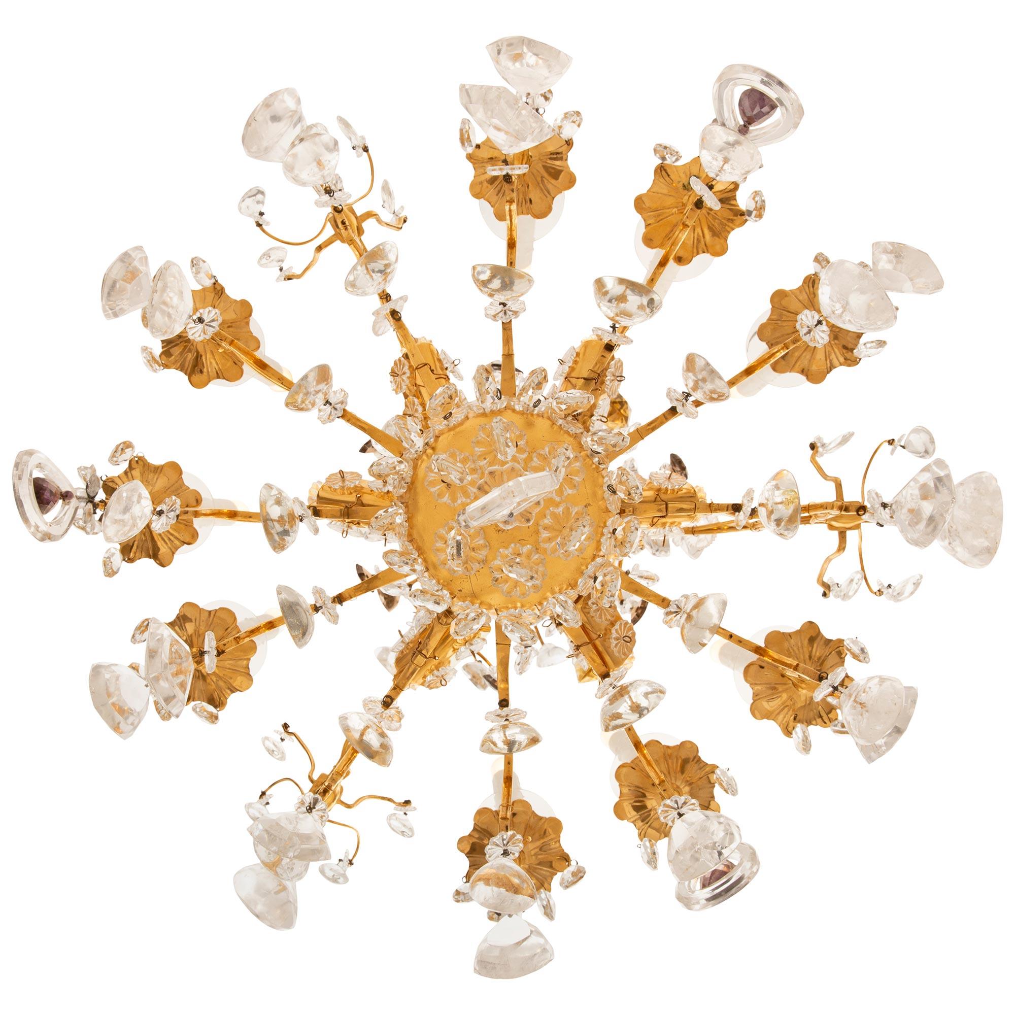 A lovely and uniquely detailed French 19th century Louis XV st. Ormolu, Crystal and Rock Crystal chandelier. This nine arm, eighteen light chandelier is centered by a most decorative pierced diamond shaped Crystal with a central tear drop. Above the