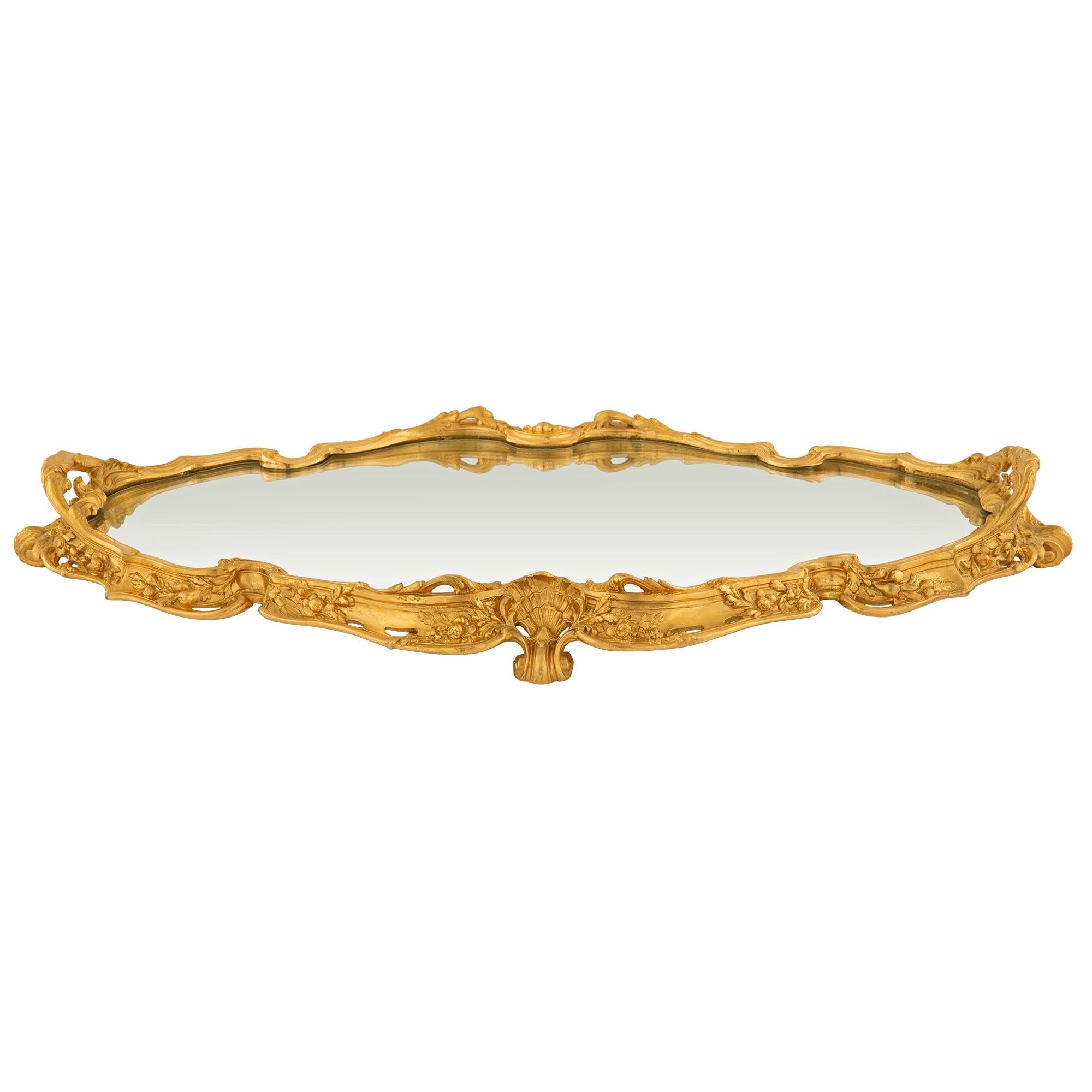 A beautiful and most decorative French 19th century Louis XV st. ormolu mirrored plateau tray. The plateau is raised by most elegant scrolled seashell feet flanked by beautiful pierced scrolled scalloped shaped foliate designs with lovely richly