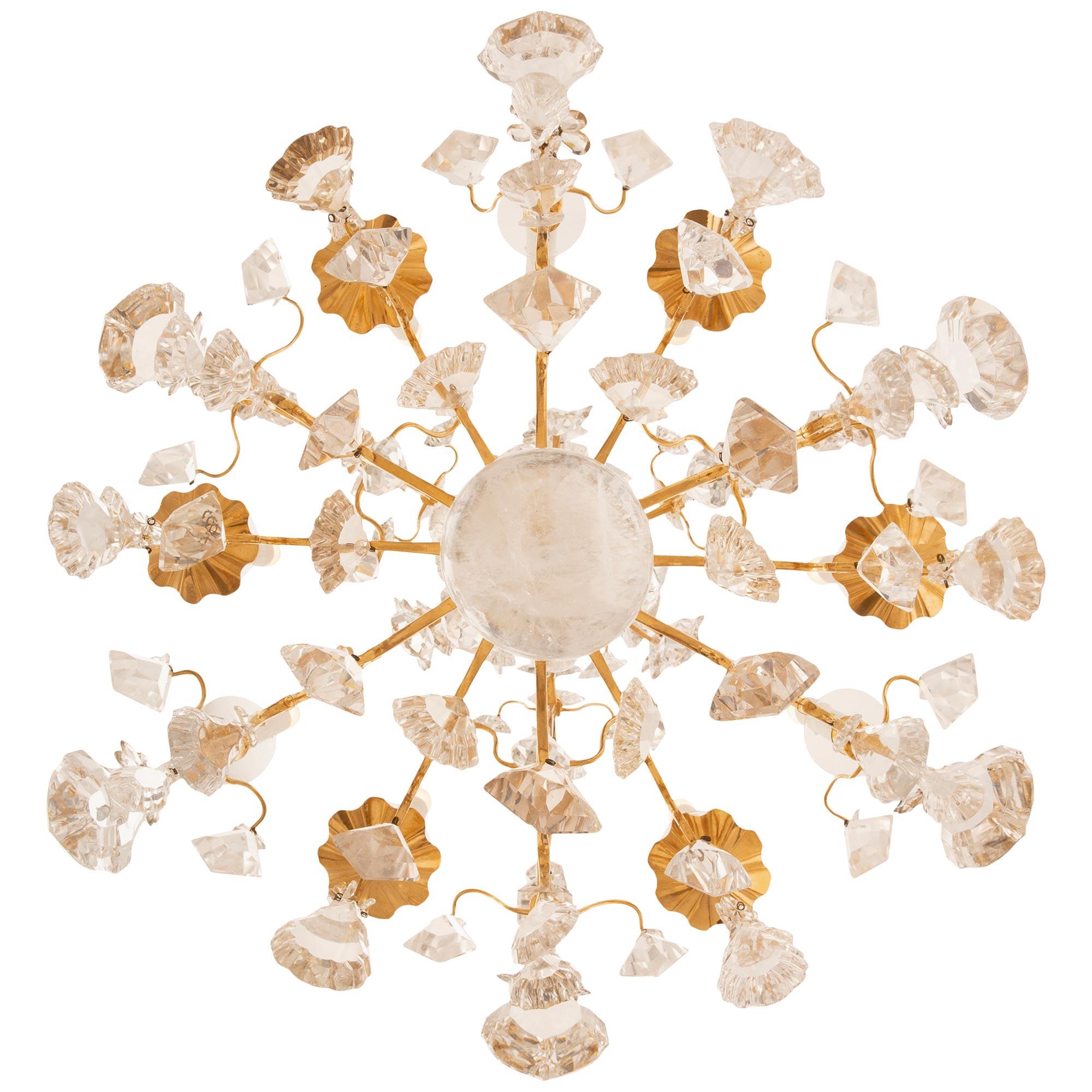A high quality French 19th century Louis XV st. Ormolu, Rock Crystal and Crystal chandelier. The nine arm open scrolled Ormolu cage has three main supporting arms with cut prisms and decorative rock crystal daggers all below additional crystals and
