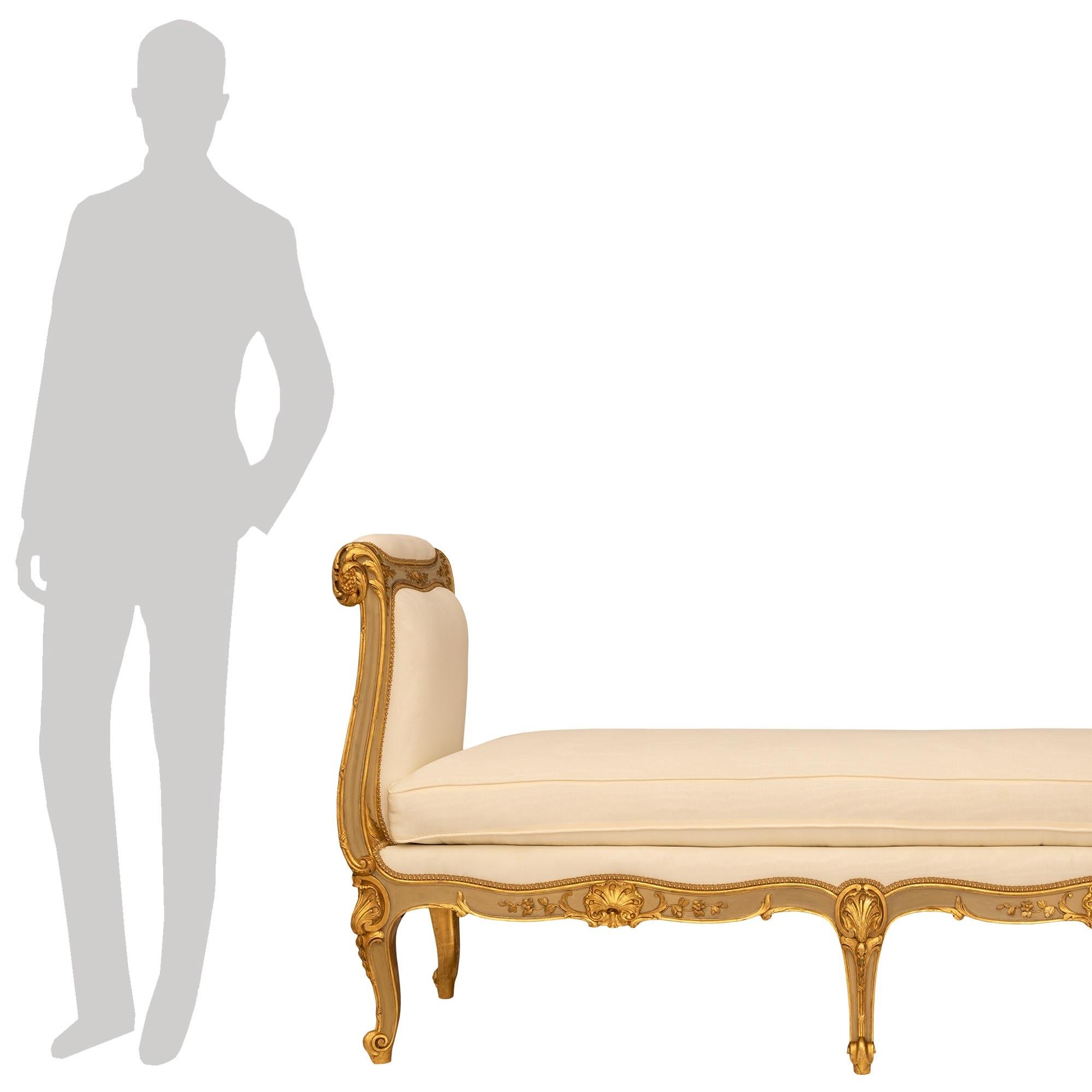 Superbe et très élégante banquette en bois patiné et doré de style Louis XV du XIXe siècle. Cette banquette exceptionnelle repose sur cinq pieds cabriole avec des pieds à volutes et des capuchons supérieurs en forme de feston. Le tablier avant, en