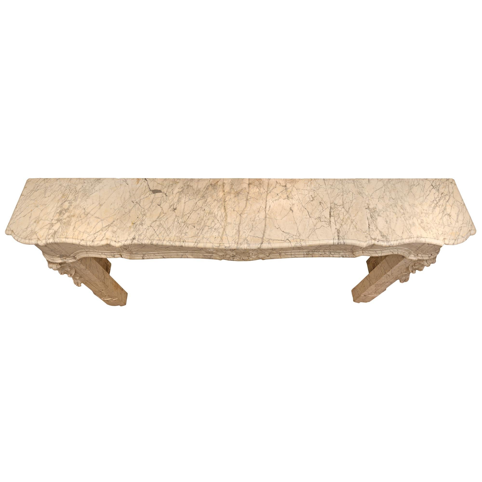 Un bellissimo caminetto in marmo Luigi XV St. Sarrancolin del XIX secolo. Il mantello è sollevato da eleganti stipiti con i disegni più decorativi incassati e foglie d'acanto riccamente scolpite. L'elegante fregio a forma di smerlo mostra un filetto