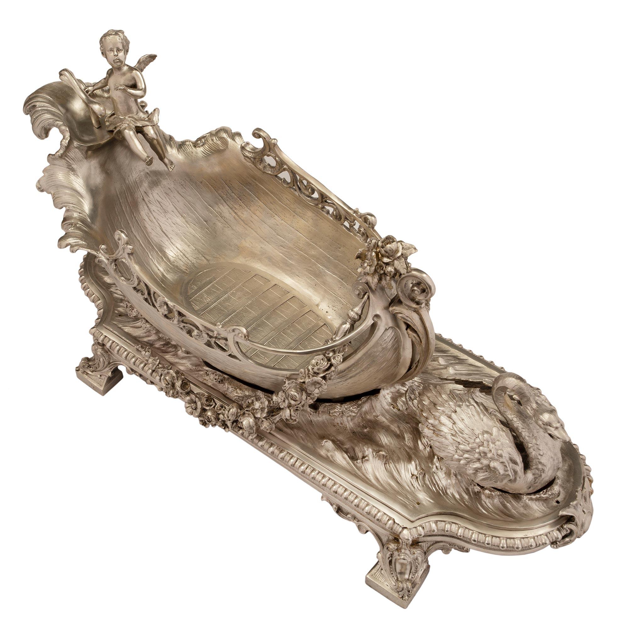 Superbe et finement ciselé centre de table en bronze argenté de style Louis XV du 19ème siècle. Le centre de table repose sur des pieds carrés à volutes ornés de feuilles d'acanthe. Au-dessus se trouve le plateau avec une bordure perlée et une