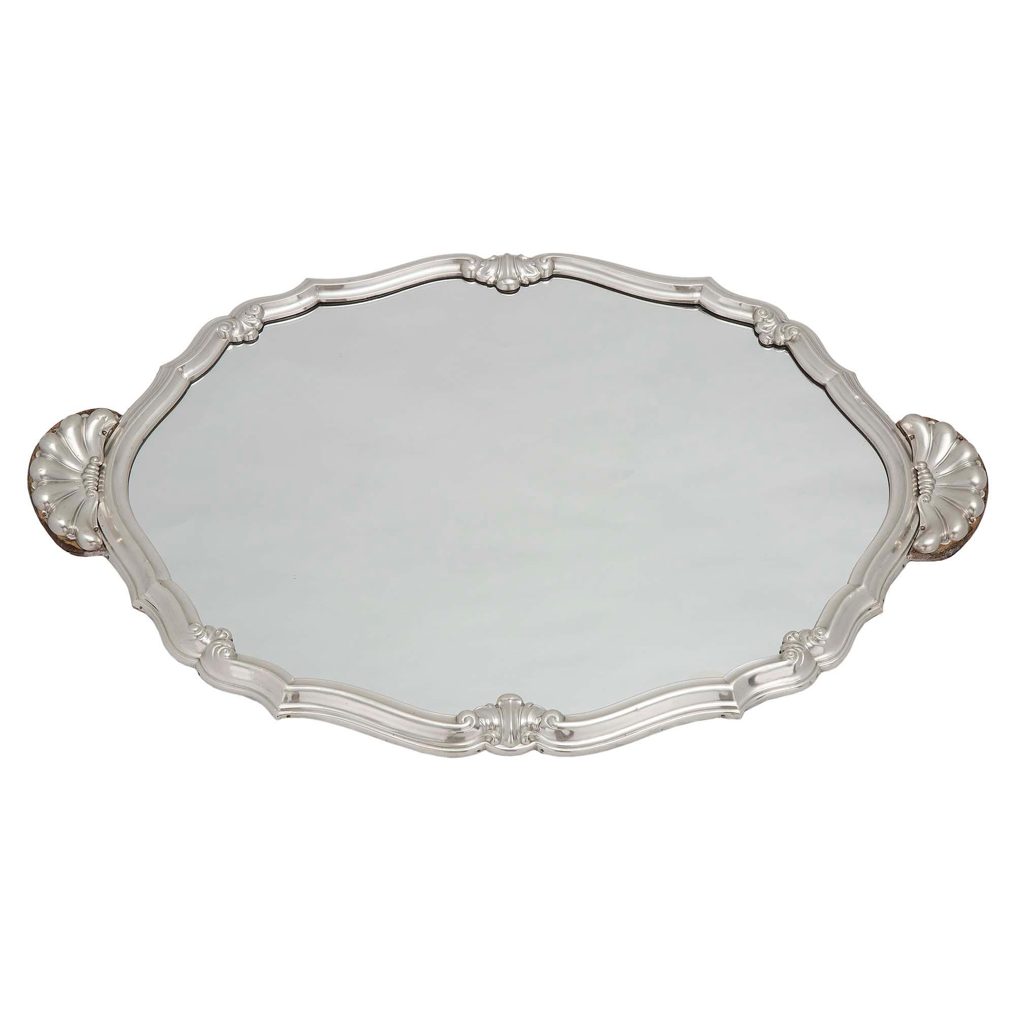 An elegant French 19th century Louis XV st. silvered bronze mirrored plateau. The centerpiece retains the original mirror plate and is framed within a fine scalloped shaped mottled silvered bronze border with decorative foliate reserves and charming