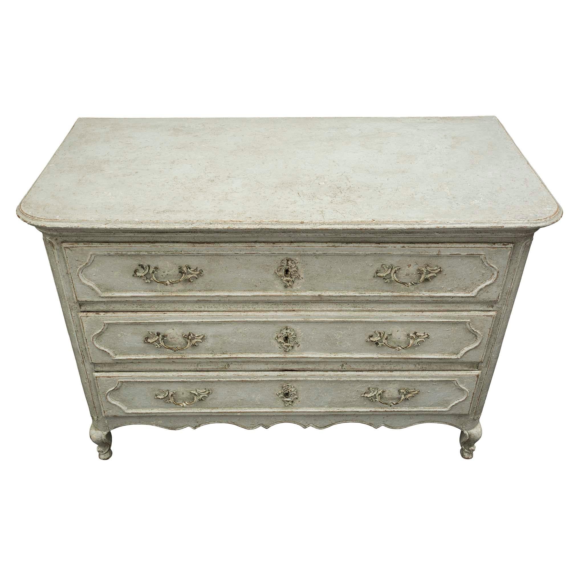 A very attractive and decorative Country French 19th century Louis XV style three drawers patinated commode. The commode is raised by cabriole legs below an elongated mottled corner design. The scalloped frieze is below the three drawers retaining