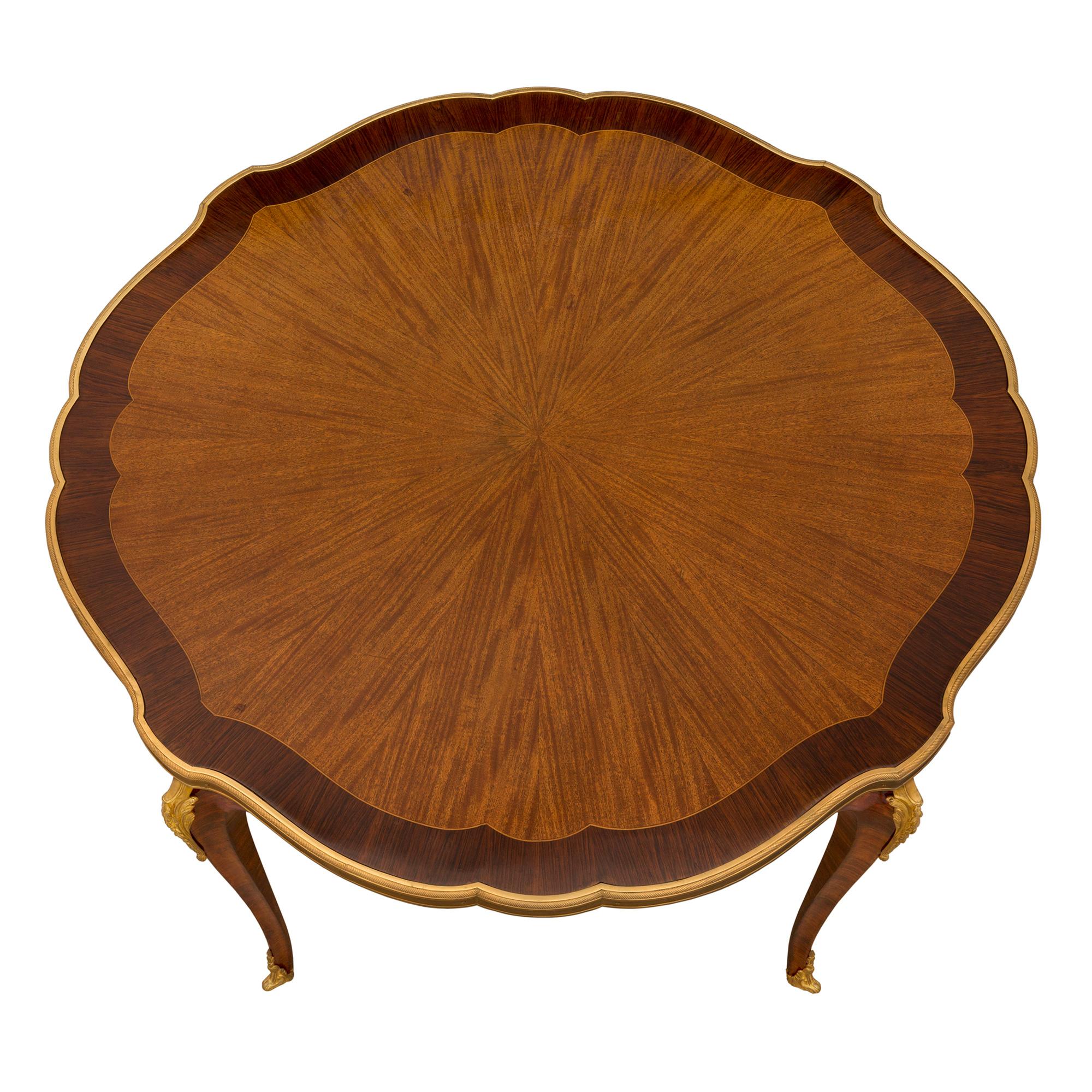 Un elegantissimo tavolo da cocktail/caffè circolare in legno di tulipano, kingwood e ormolu del XIX secolo. Il tavolo è sollevato da quattro sottili gambe cabriole che mettono in mostra le bellissime venature del legno di re, con raffinati sabot