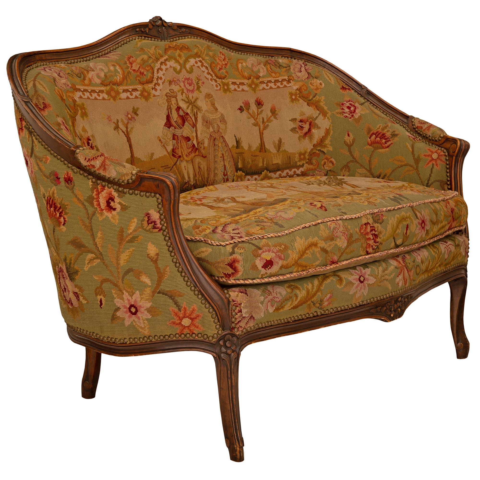 A charming French 19th century Louis XV st. Walnut and tapestry settee. The settee is raised by elegant cabriole legs with finely carved mottled fillets which extend along the frieze centered by richly carved flowers. The mottled fillets extend up