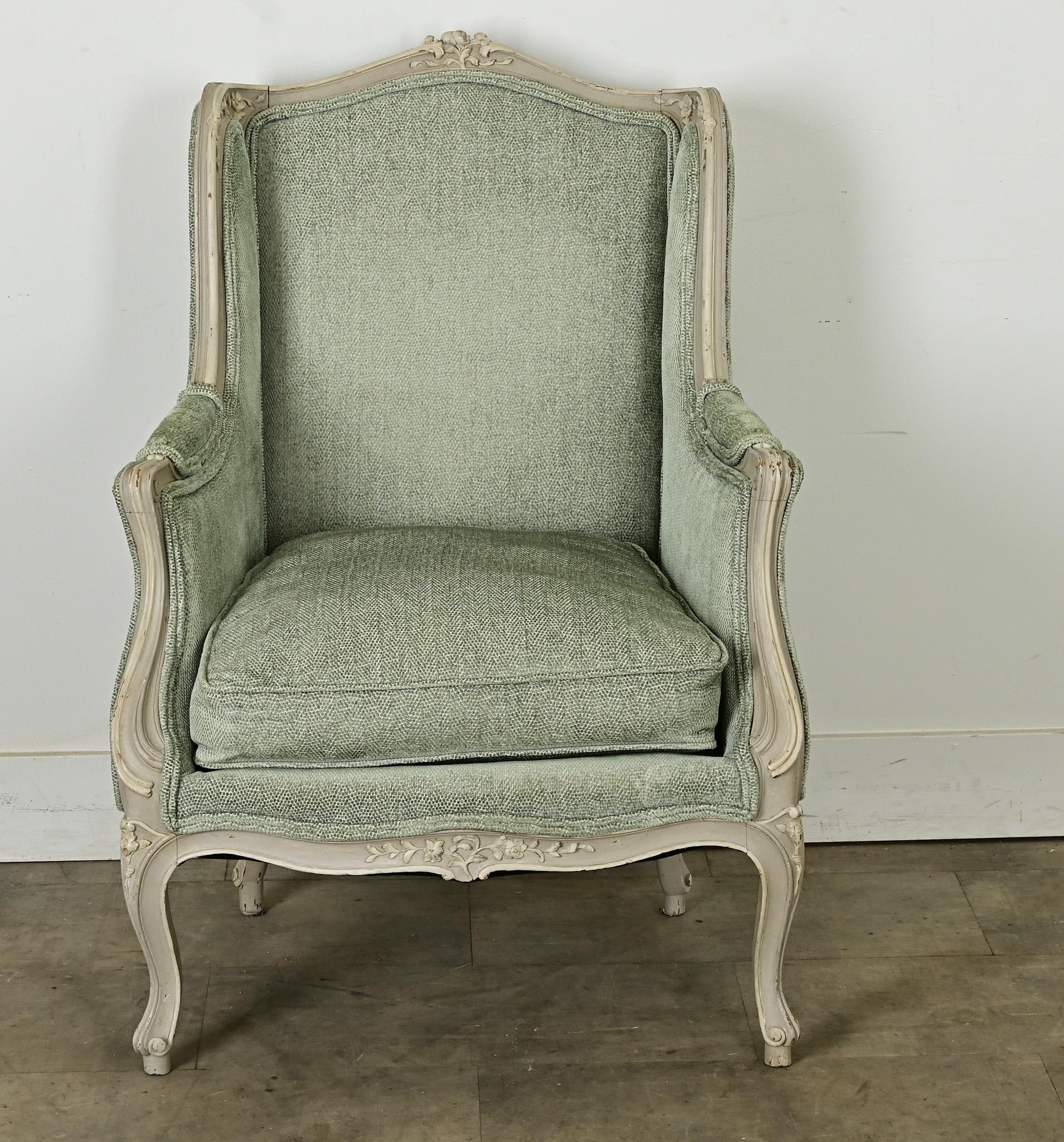 In a lovely aquamarine upholstery on gray painted frame, this beautiful French 19th century Louis XV style bergere has timeless appeal. Crowned with a delicate posy carving in the arched back, the fluted and floral details extend down the frame