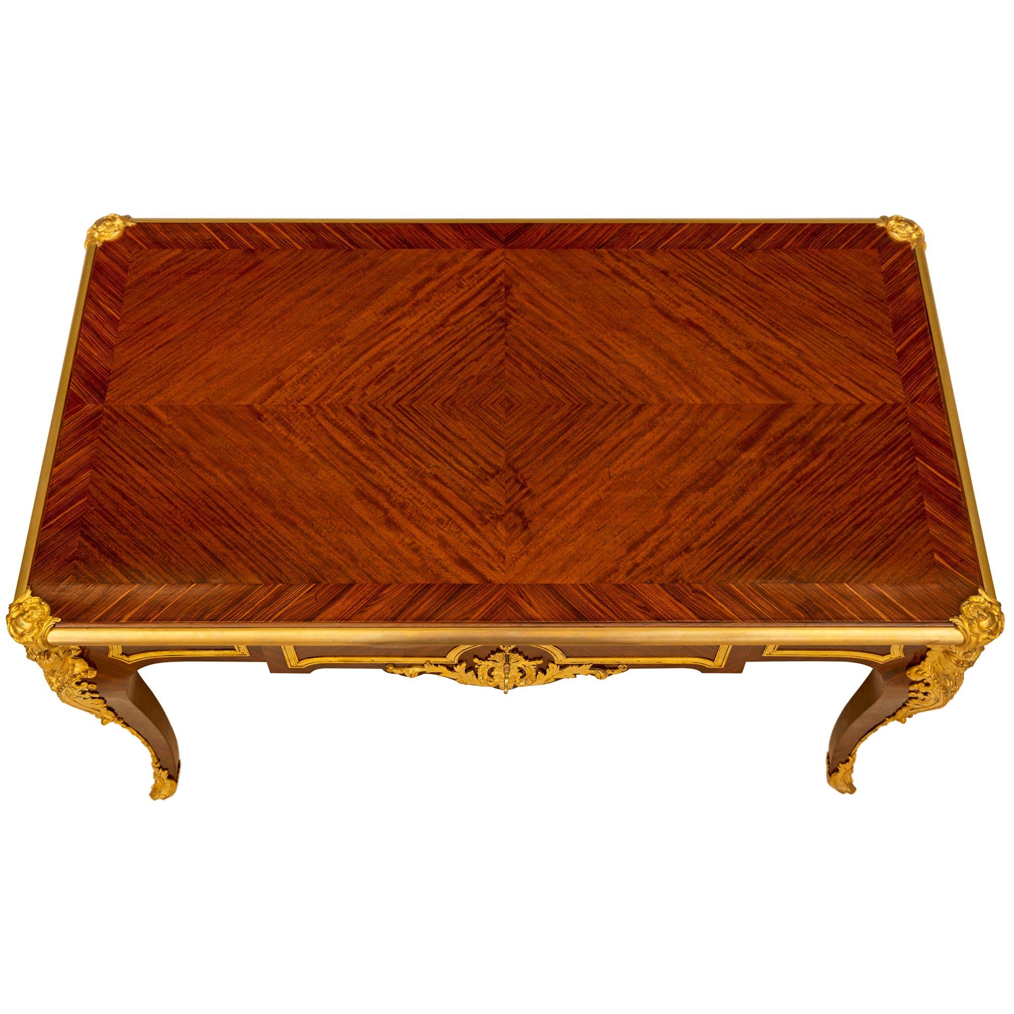 Uno splendido Bureau Plat in legno di re e tulipano in stile Luigi XV del XIX secolo, firmato Sormani, Parigi. Si erge su quattro gambe cabriole con sabot avvolgenti in ormolu e scivoli in ormolu. Le montature in ormolu finemente cesellate con i