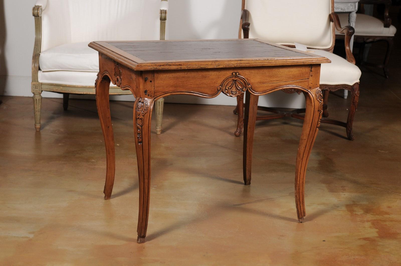 A French Louis XV style carved walnut side table from the 19th century, with leather top and cabriole legs. Born in France during the politically dynamic 19th century, this walnut table features a rectangular top with beveled edges and leather