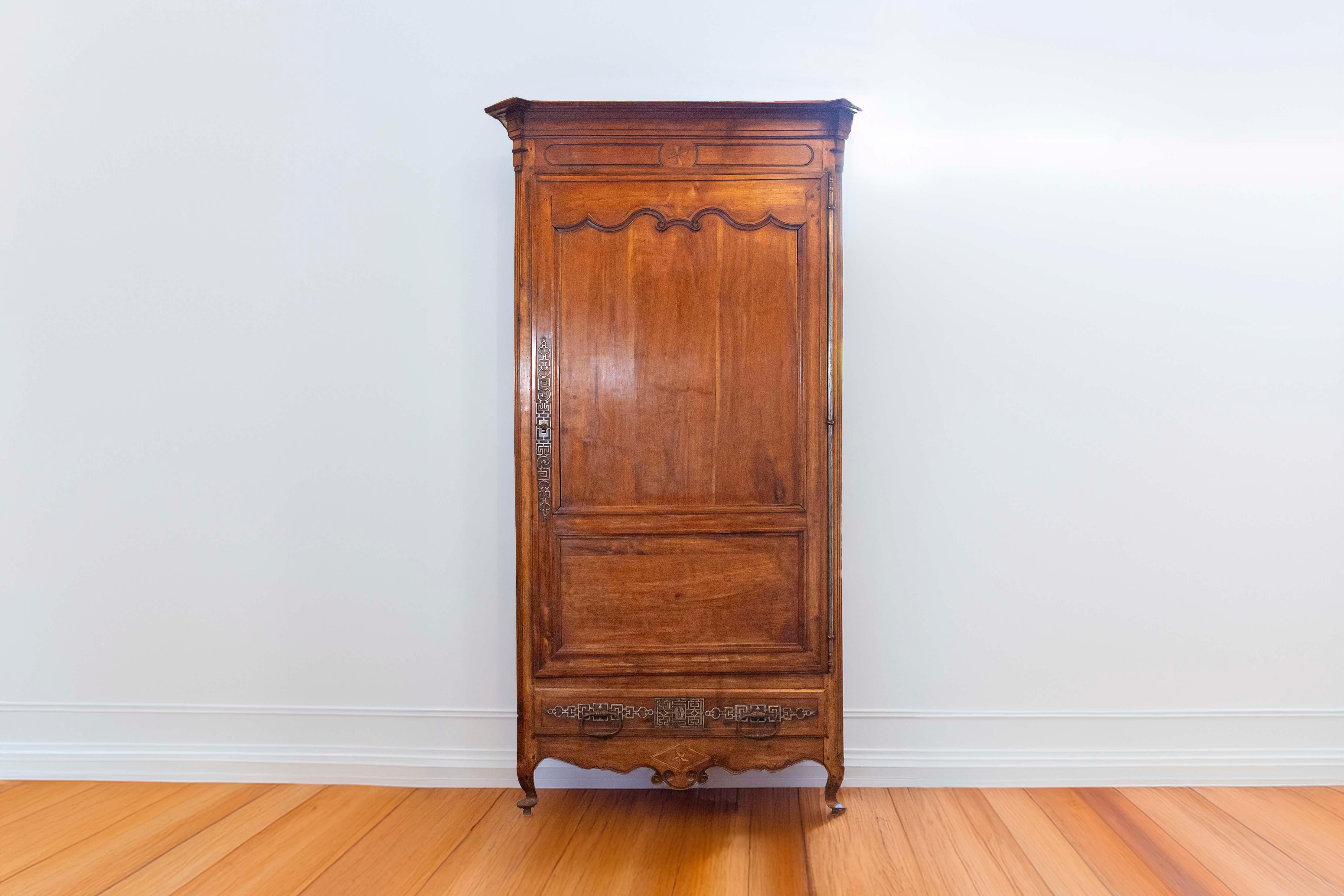 A French early 19th century cherry wood Louis XV style bonnetière from the Charente Region. This French cabinet was born in the Southwestern region of Charente (think Angoulême) , famous for its traditional production of salt and cognac. Originally
