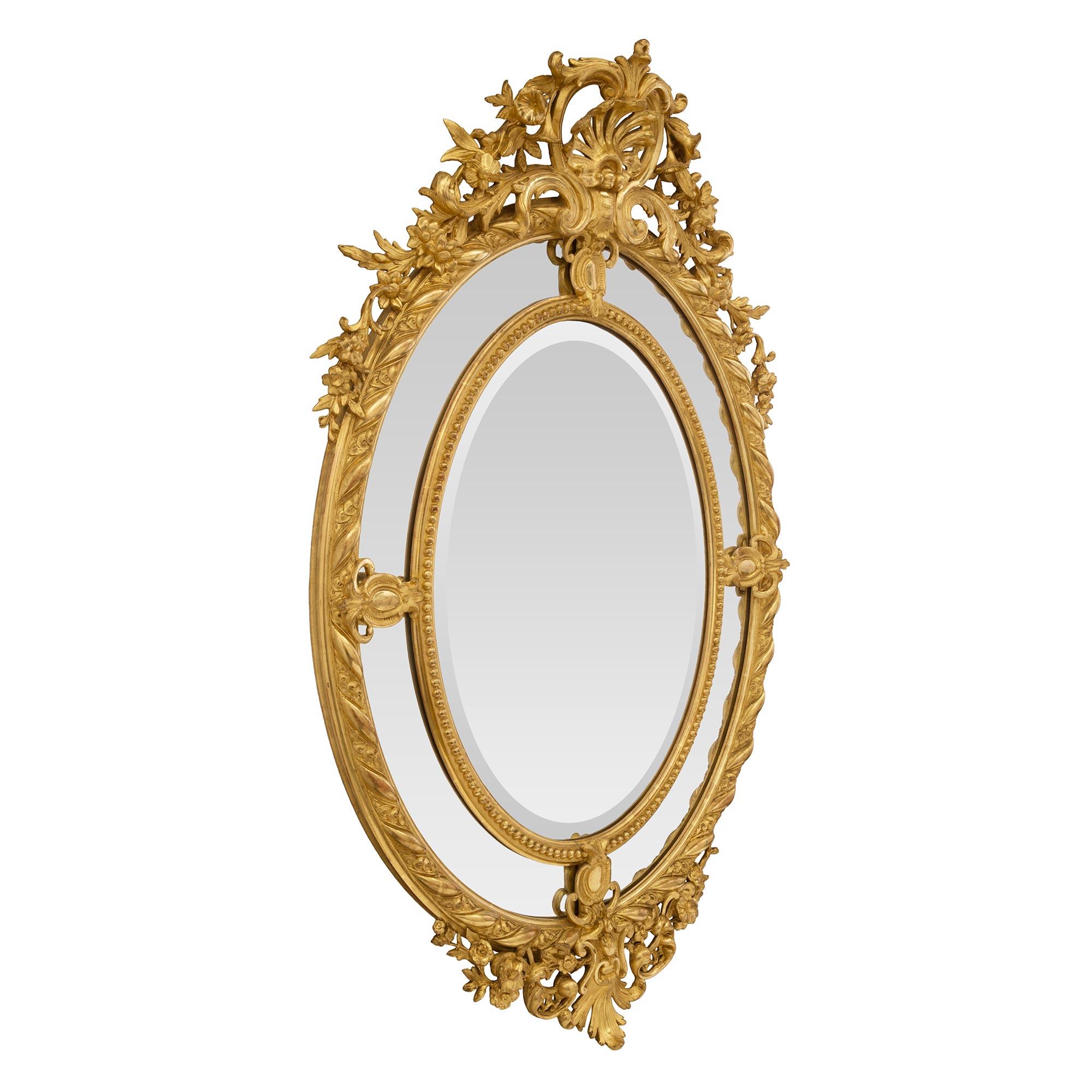 Superbe miroir ovale en bois doré à double cadre, de style Louis XV, datant du XIXe siècle. Le miroir central biseauté d'origine est encadré d'une fine bande perlée. Les quatre plaques de miroir extérieures originales sont séparées par de jolis