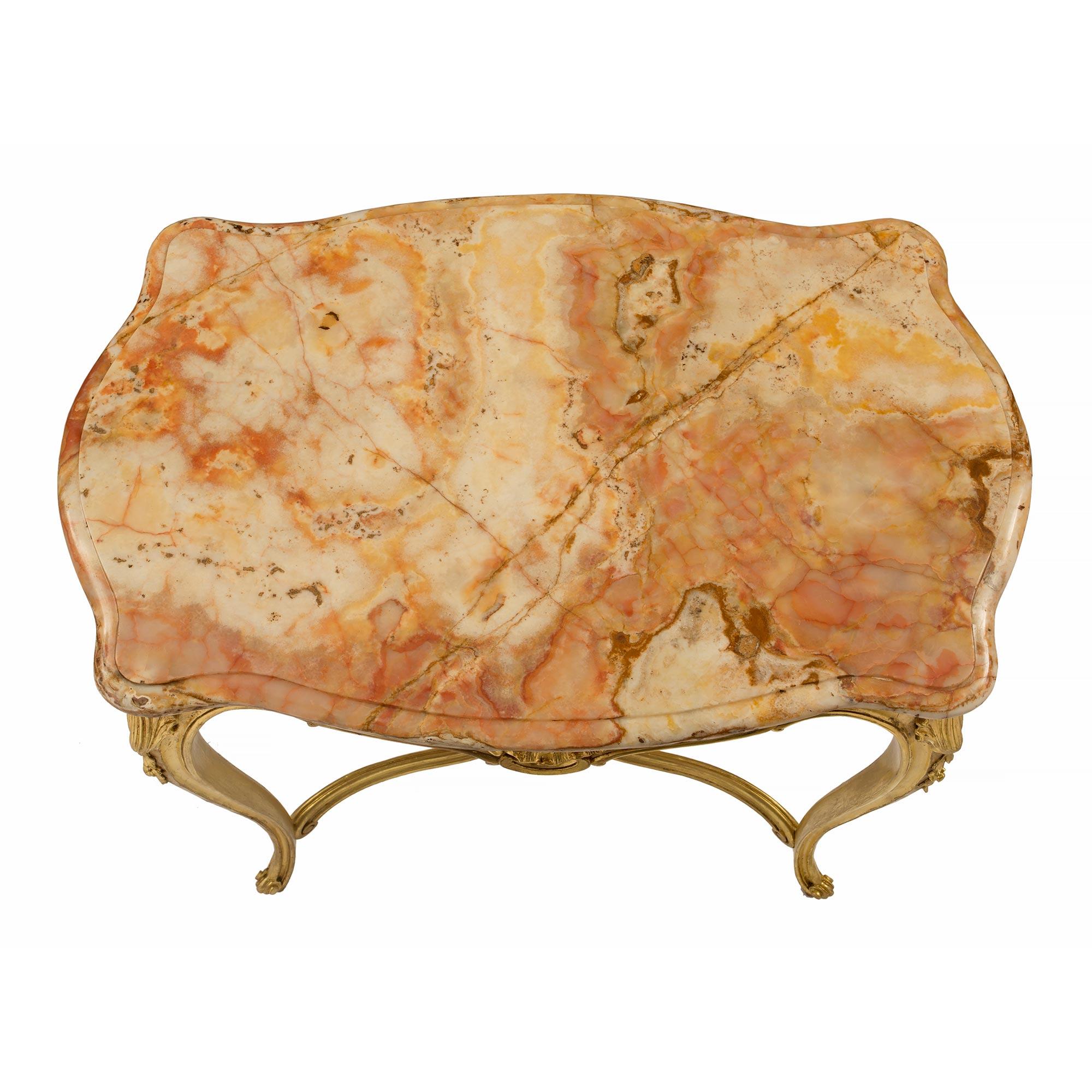 A most elegant French 19th century Louis XV st. giltwood and marble side/center table. The beautiful scalloped shape table is raised by slender cabriole legs with fine scrolled feet. Each leg is connected by a striking X shaped stretcher with a