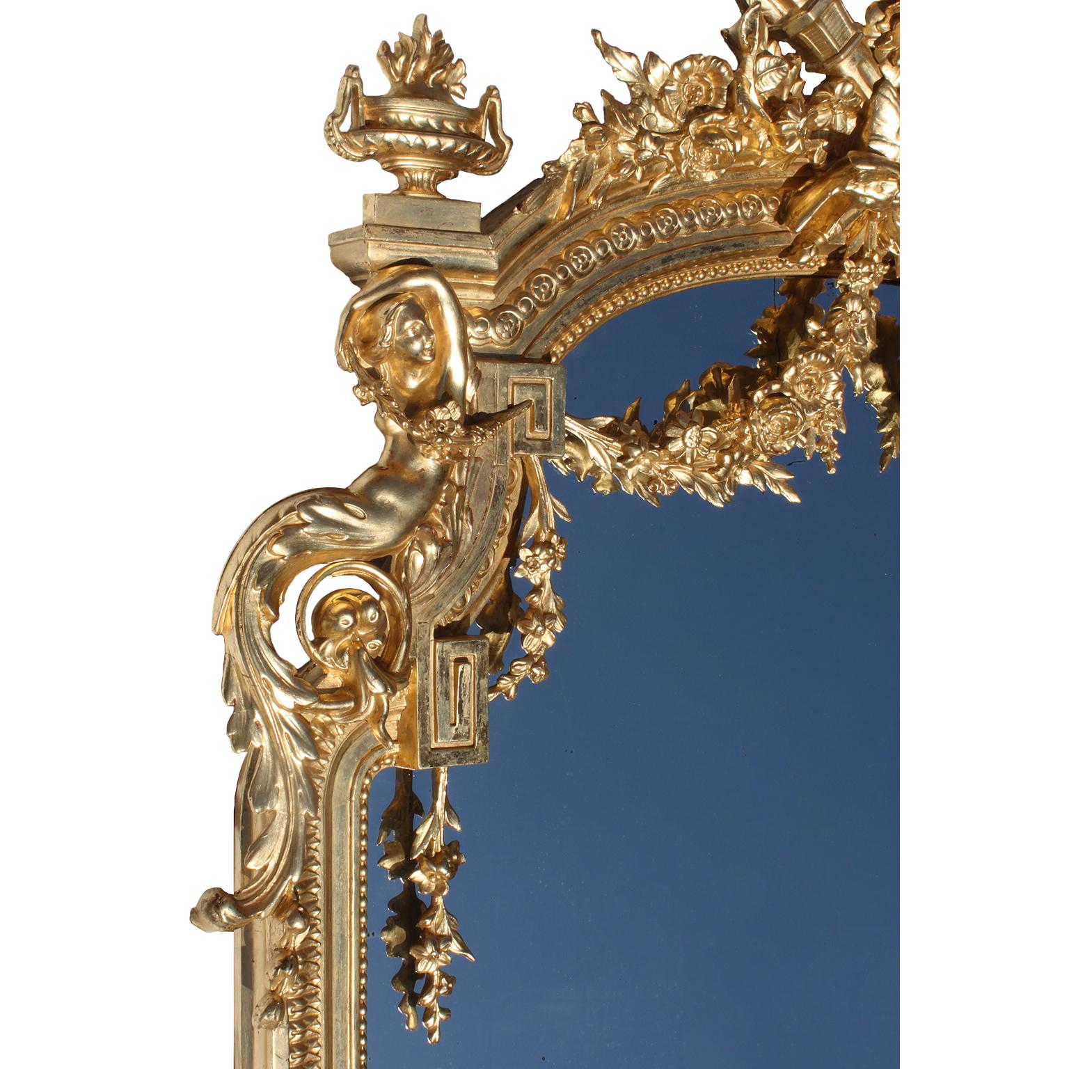 A fine French 19th century Louis XV style giltwood and Gesso carved figural mirror. The elongated frame crowned with a pair of allegorical kissing birds among floral bouquets, a crossed torch and quiver above floral garlands and flanked on each side