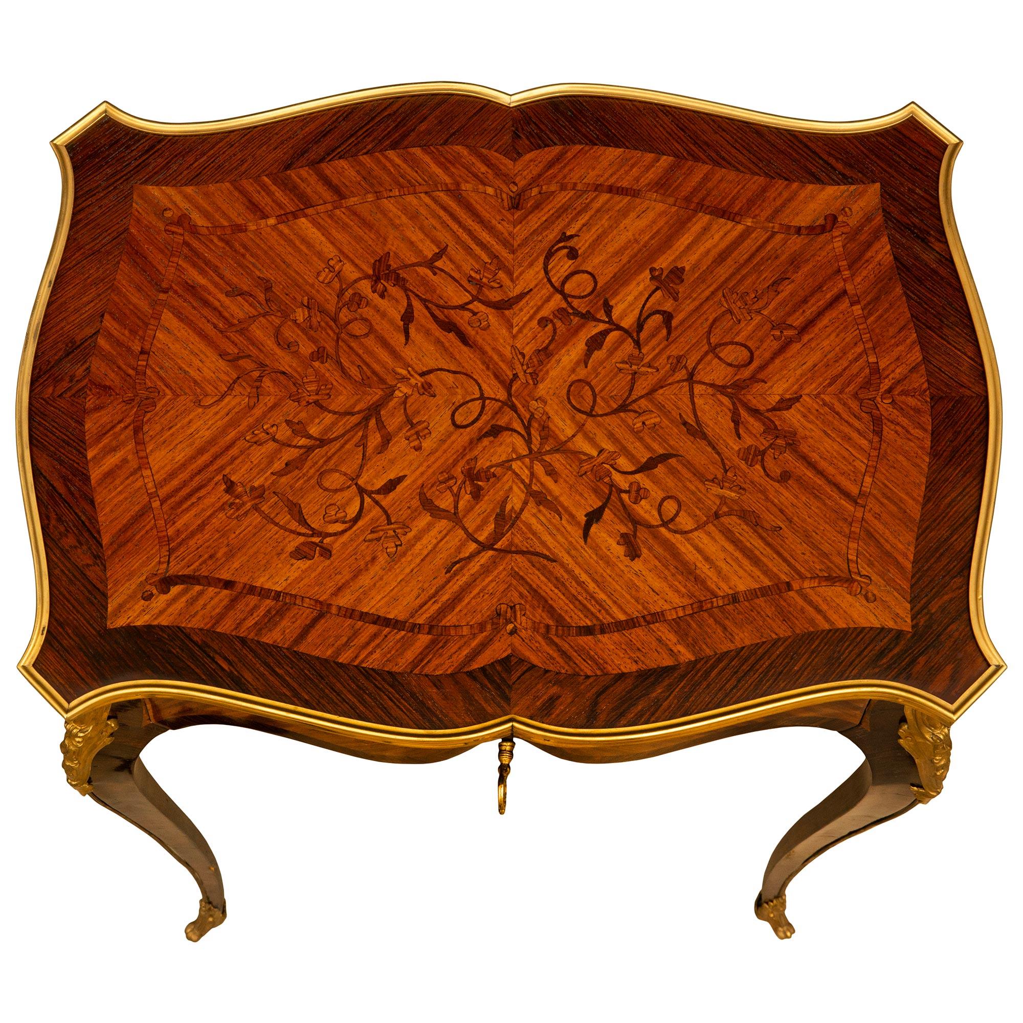 Superbe et élégante table d'appoint française du milieu du 19ème siècle, de style Louis XV, en bois de roi et bois de tulipe. La table de forme festonnée est surélevée par des pieds cabriole allongés, décorés de chutes en bronze doré se terminant