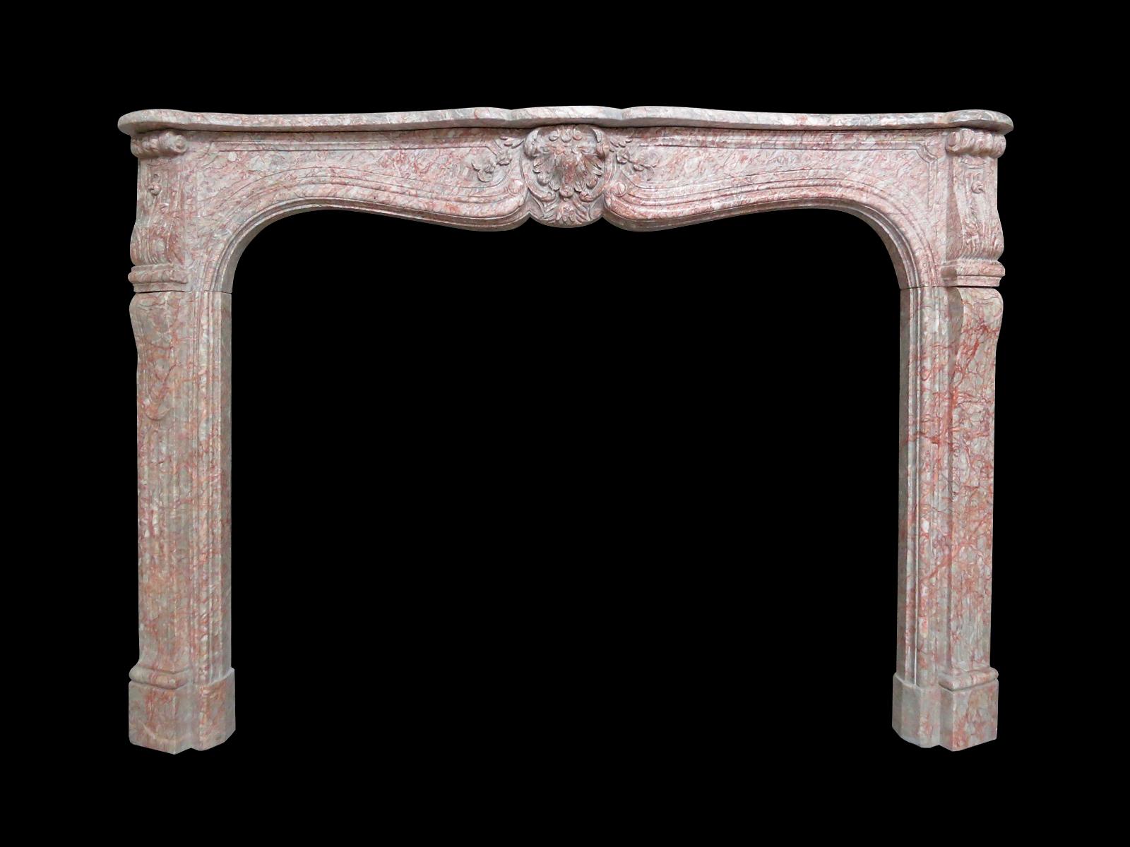 An antique surround in grey and pinkish red variegated marble. The frieze with carved shell to centre with C-scrolled and stiff acanthus end blocks. All beneath a generous serpentine shelf. 

Opening 120cm wide x 95cm high.