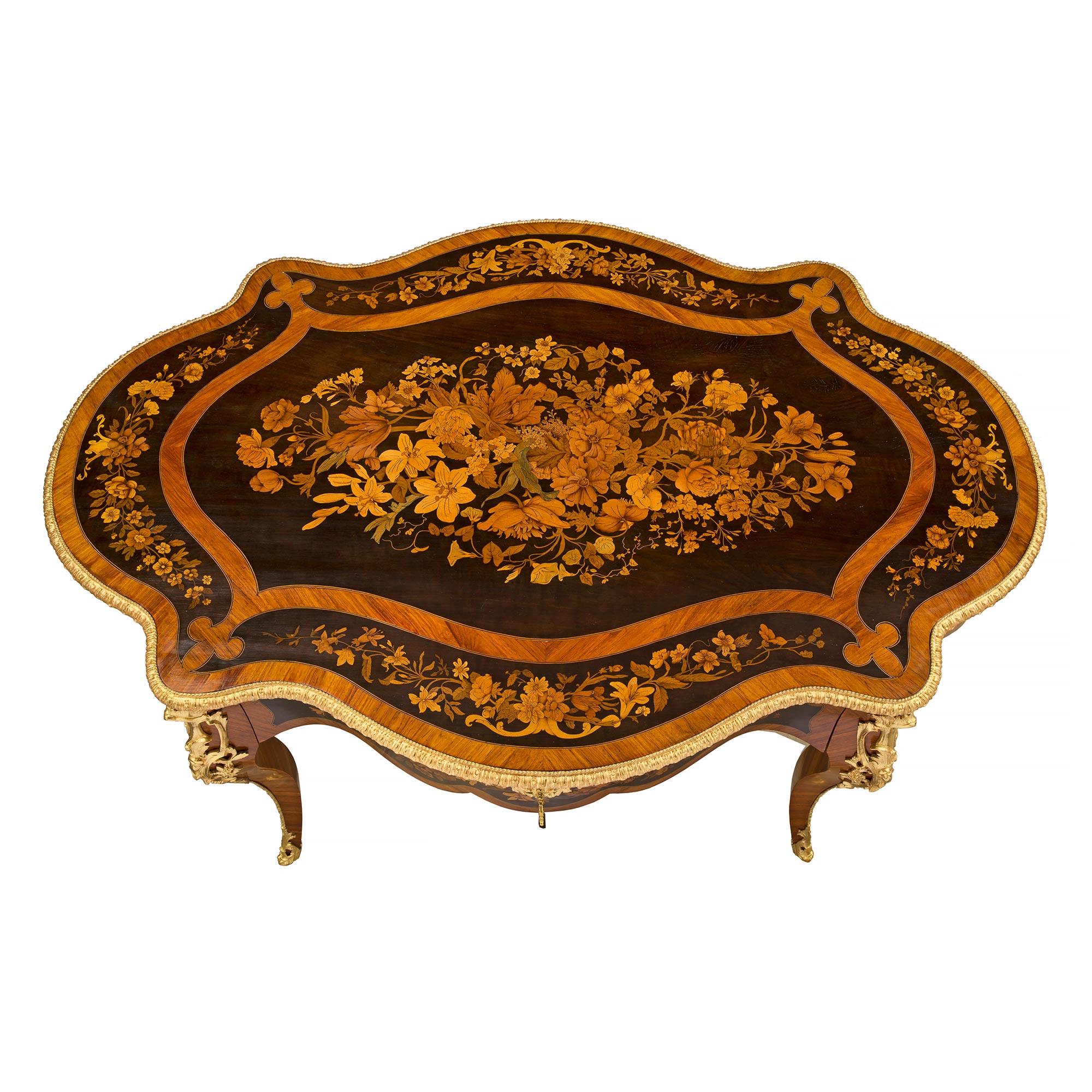A striking French 19th century Louis XV st. Napoleon III period exotic wood marquetry and ormolu center table. The table is raised by elegant cabriole legs with beautiful pierced wrap around foliate ormolu sabots and a fine fillet which extends up