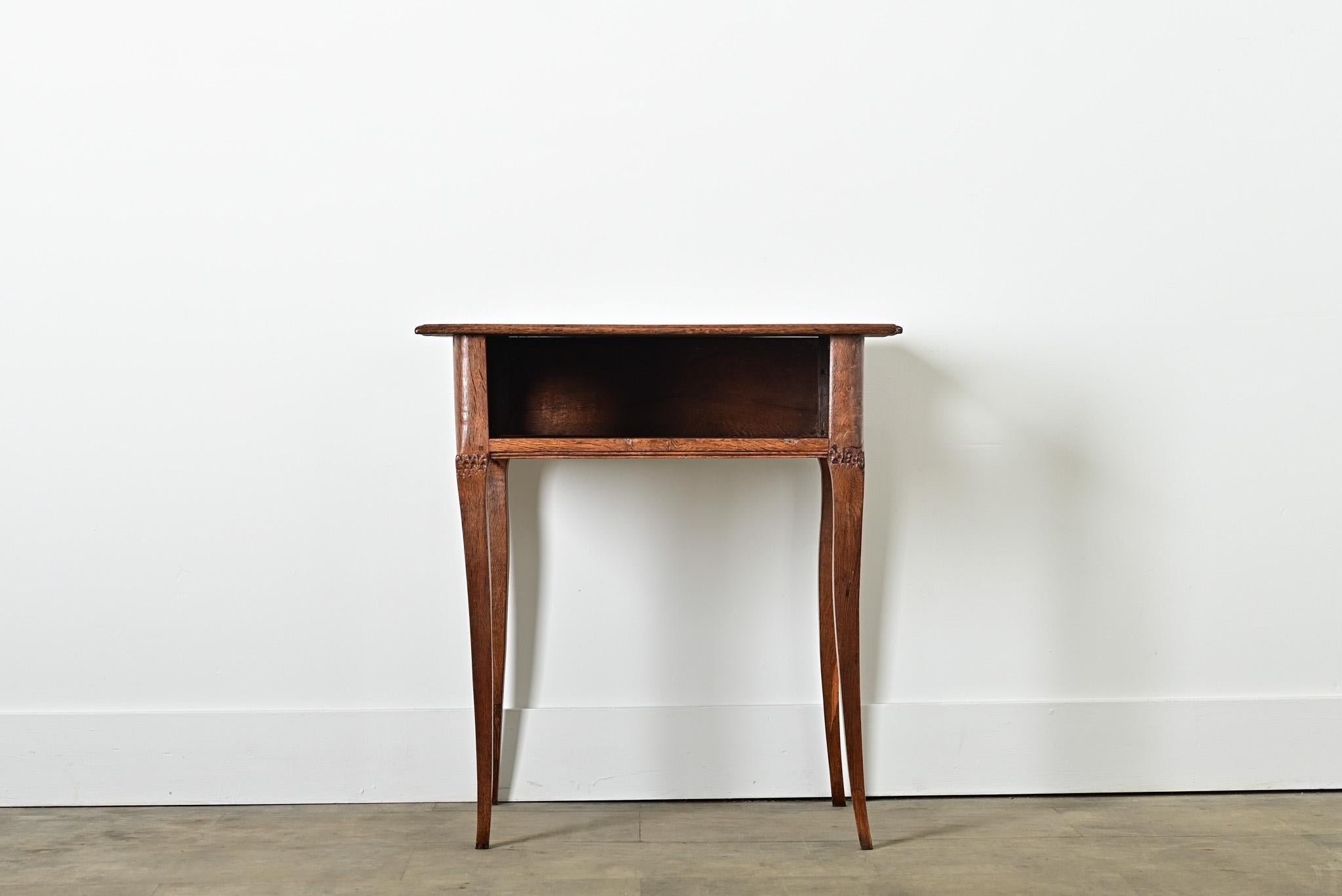 A sweet Louis XV style 19th century oak table de chevet, or bedside table, the dainty scale could be used as a side table in nearly any room around the home. The lightly patinated top surface creates an overhang above an open compartment, pierced on
