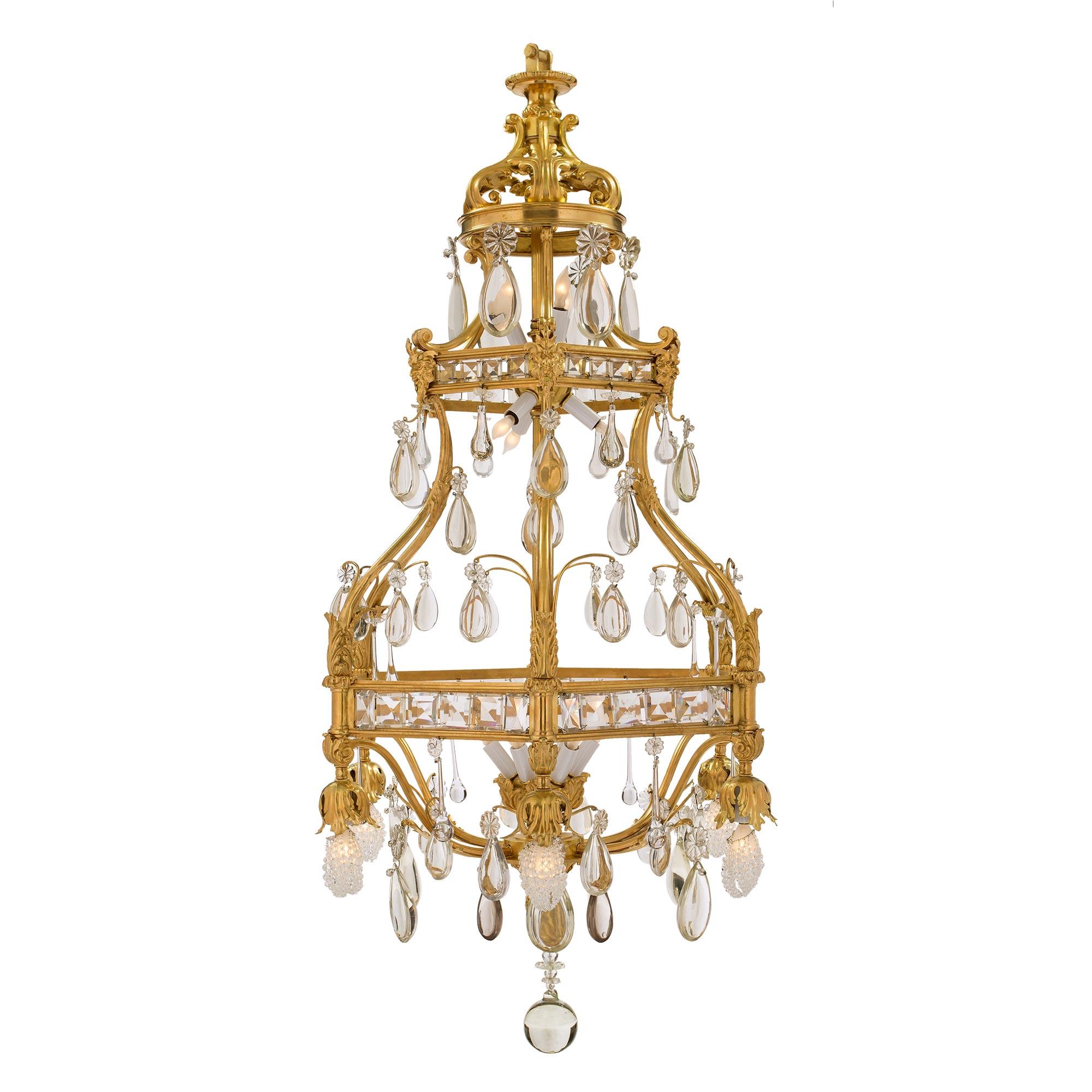 A stunning and very unique French 19th century Louis XV st. ormolu and Baccarat crystal eighteen light chandelier. At the bottom is a solid crystal ball below a fine ormolu foliate finial. Branching out at the base are elegant ormolu movements with