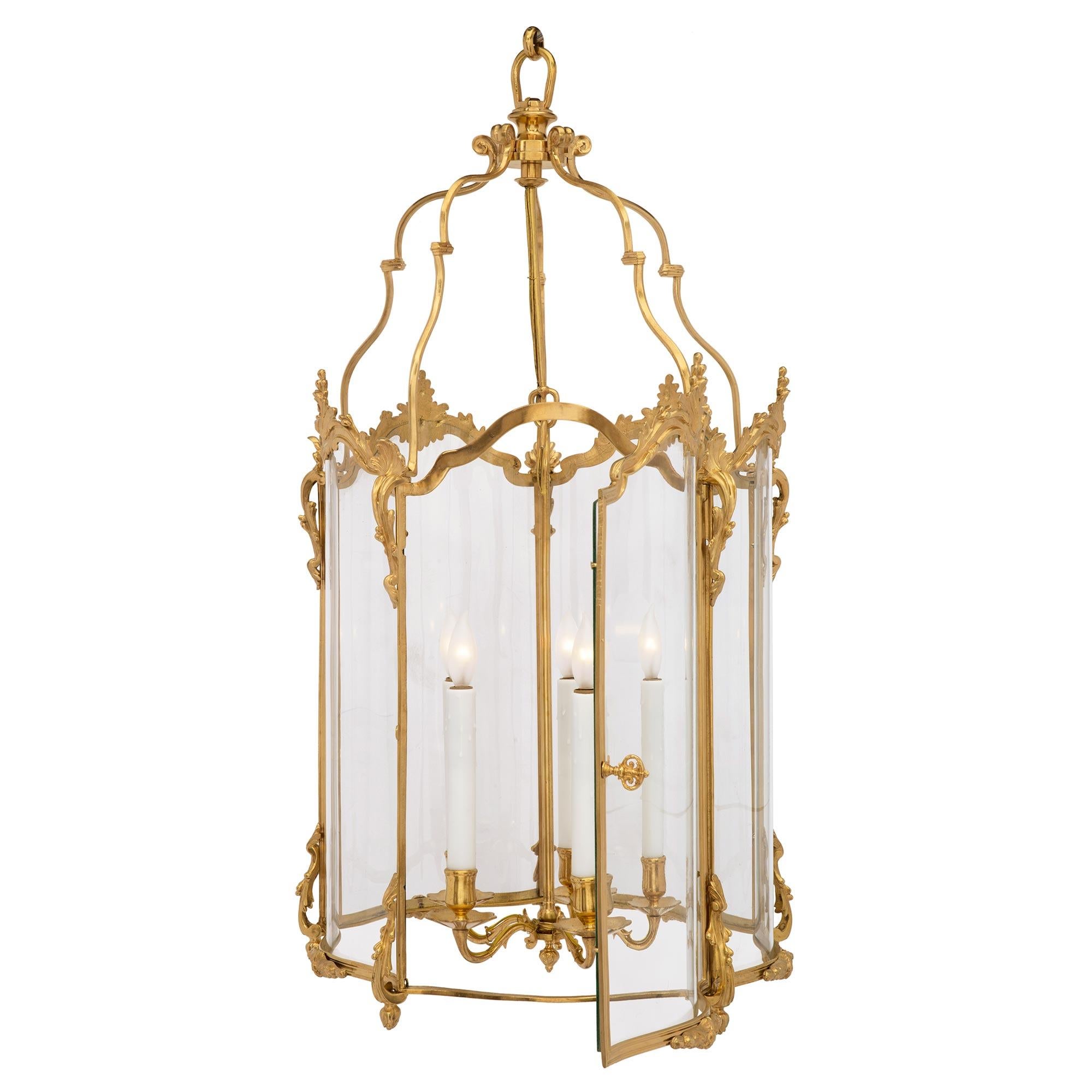 An elegant French 19th century Louis XV st. ormolu and hand blown glass lantern. The lantern is centered by a central hanging electrified ormolu pendant with five candles above candle cups and saucers. At the mottled bottom border are foliate