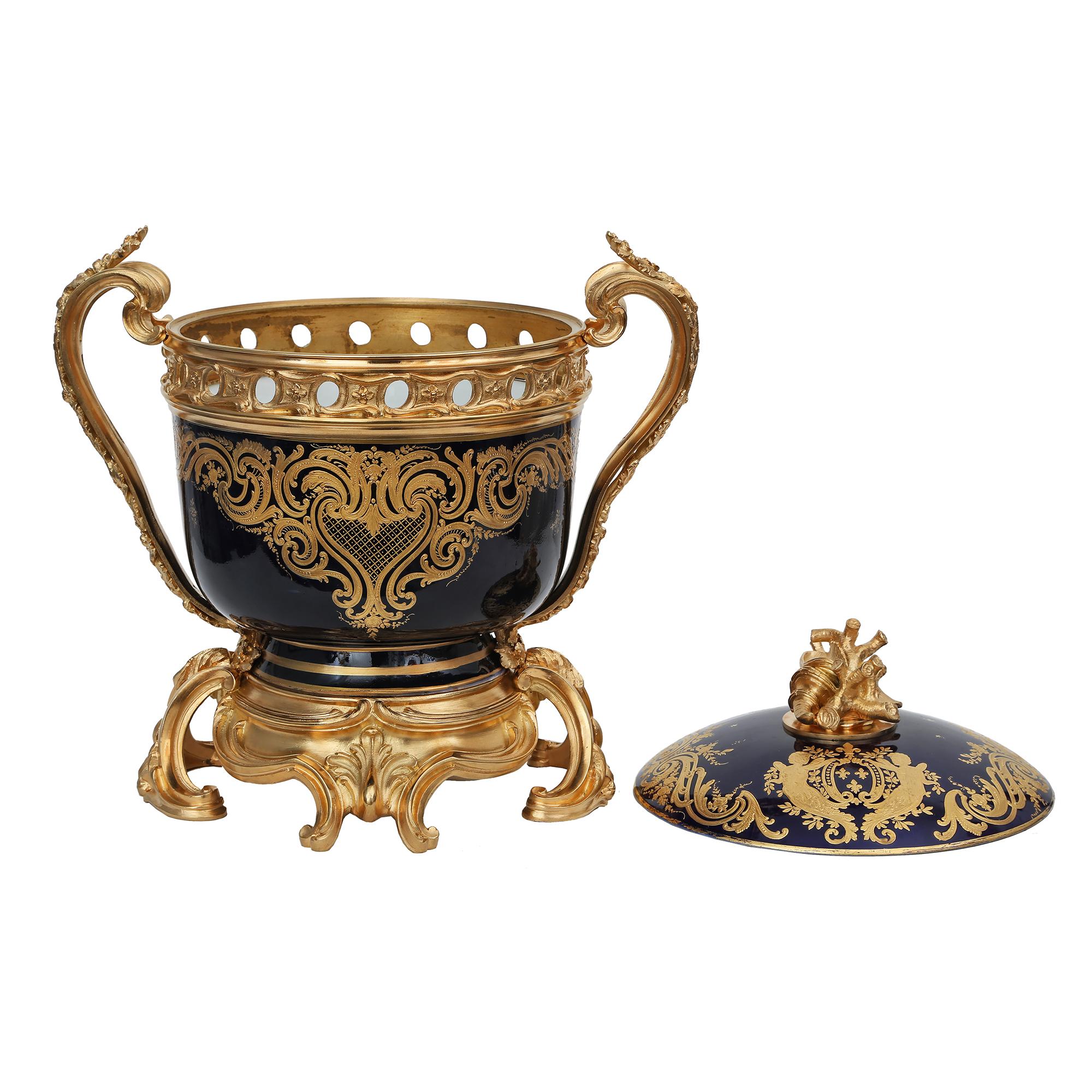 An exquisite French 19th century Louis XV st. royal cobalt blue porcelain and ormolu tureen signed Sèvres. The tureen is raised by a rich scrolled ormolu support with rich large acanthus leaves and seashell cabochons in a satin and burnished finish.
